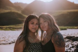 Friends sharing an intimate moment on the beach during golden hour.