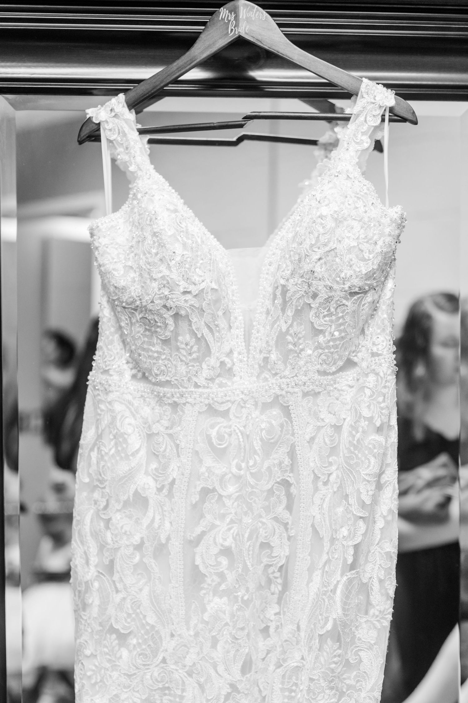 Elegant white lace wedding dress with beaded details hanging on display.