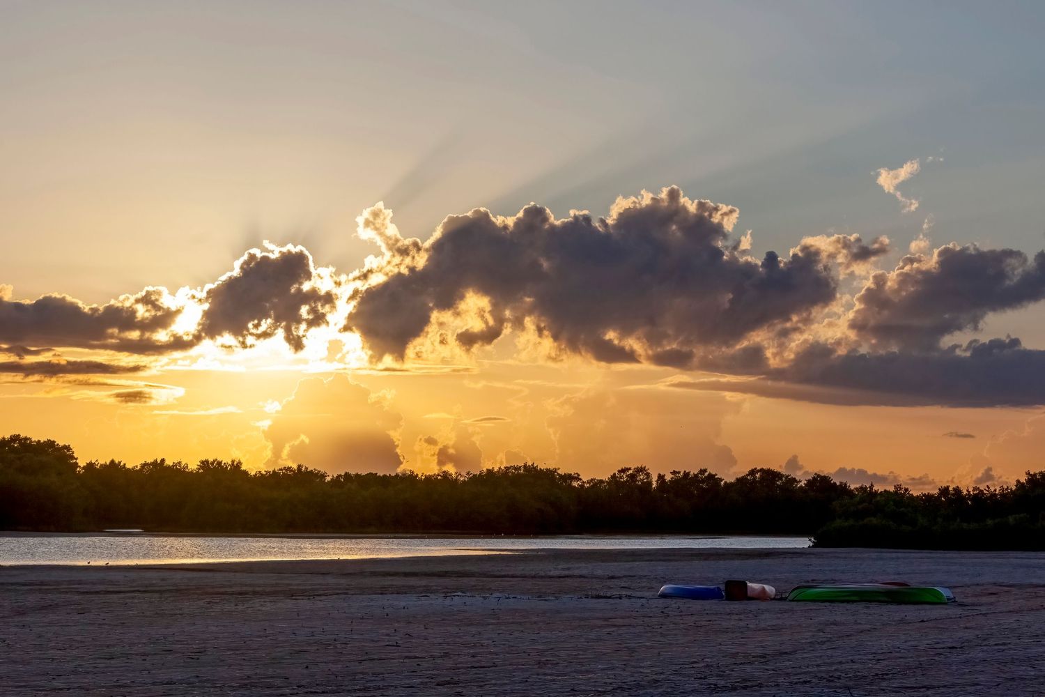 sunset over Tiger Tail Beach Lagoon with kayaks laying on the sandy beach on Marco Island, Florida