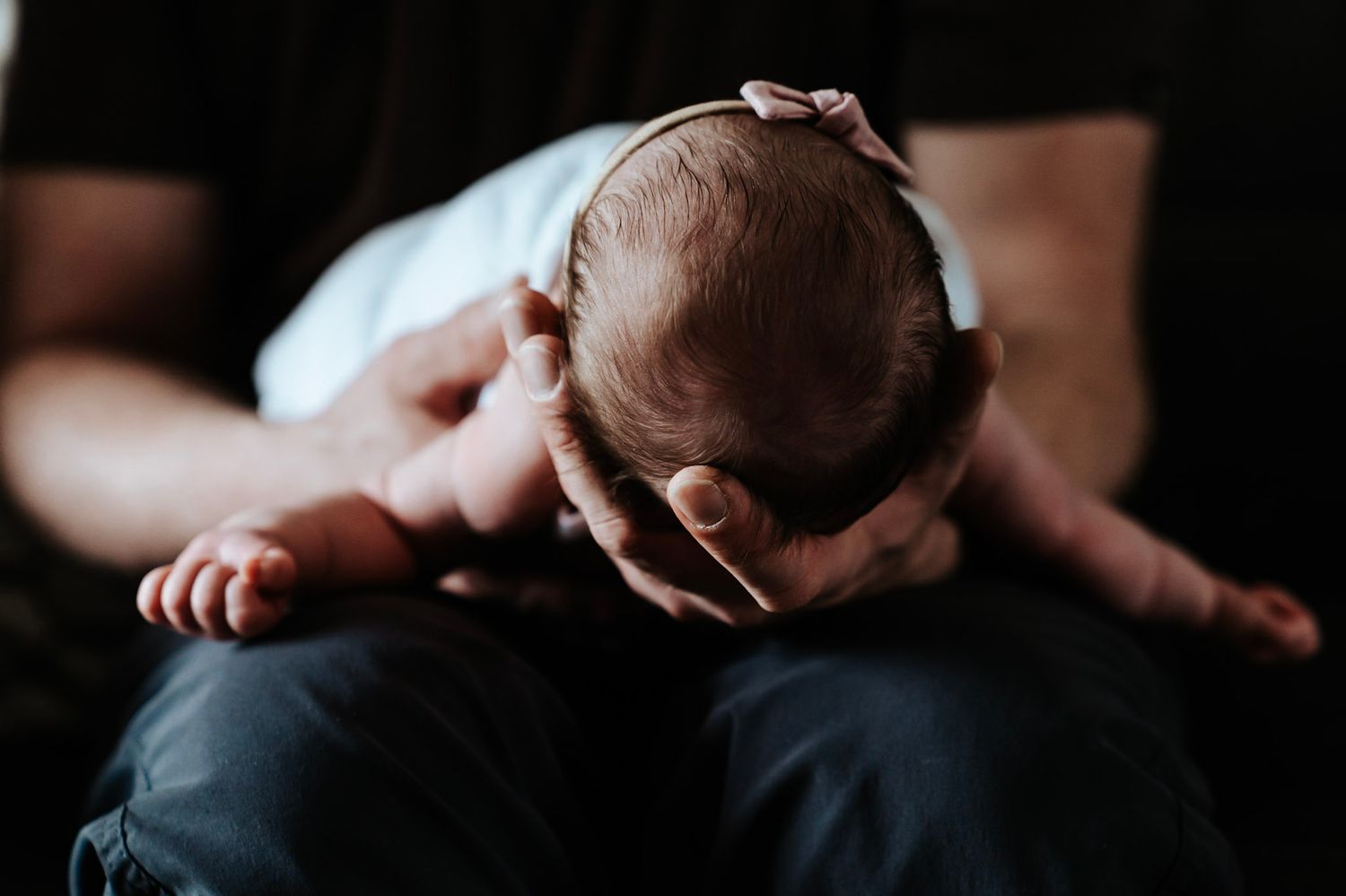 Dad holding baby girl wearing a pink bow.