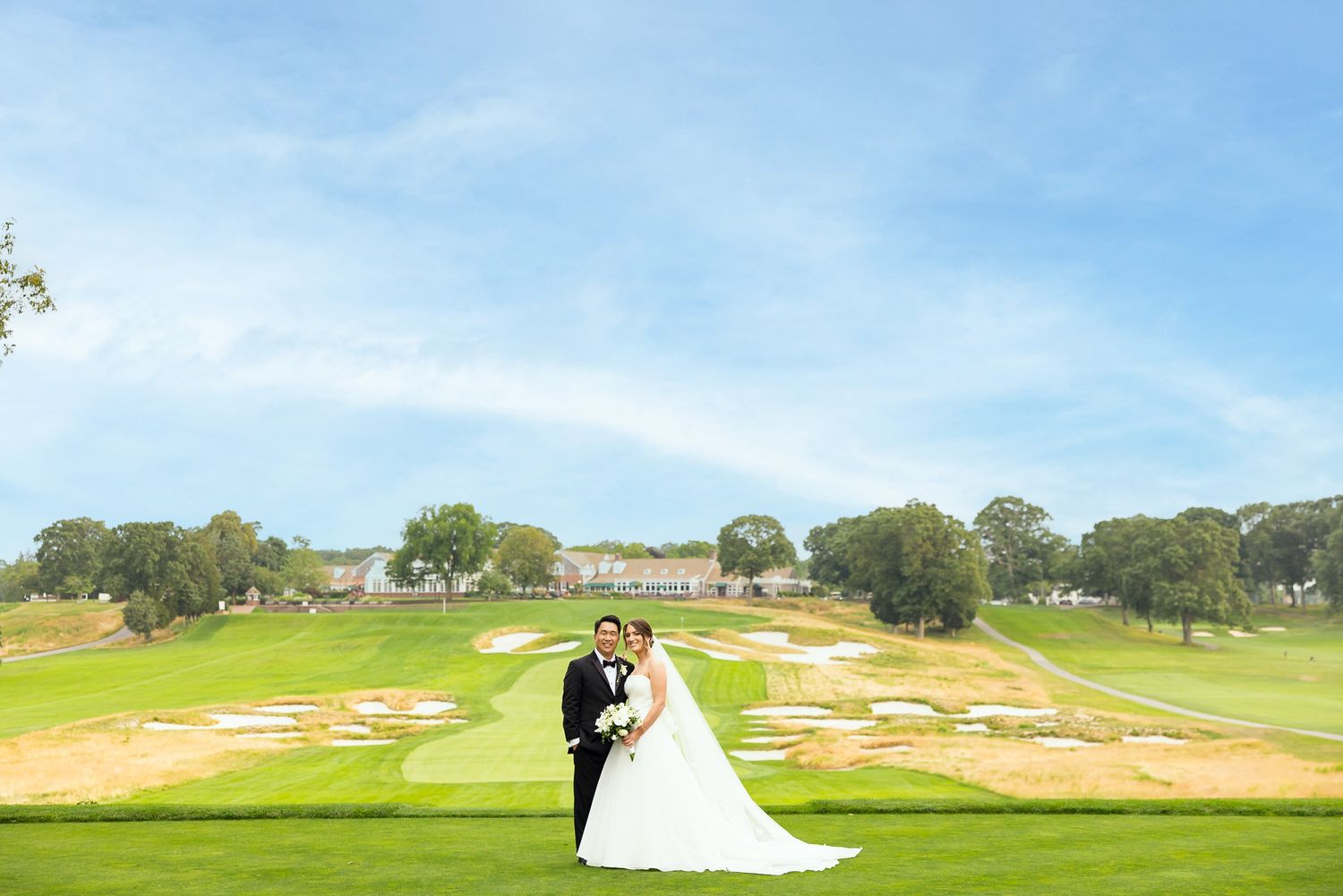 Elegant wedding portrait on a scenic golf course with rolling hills and sand traps.