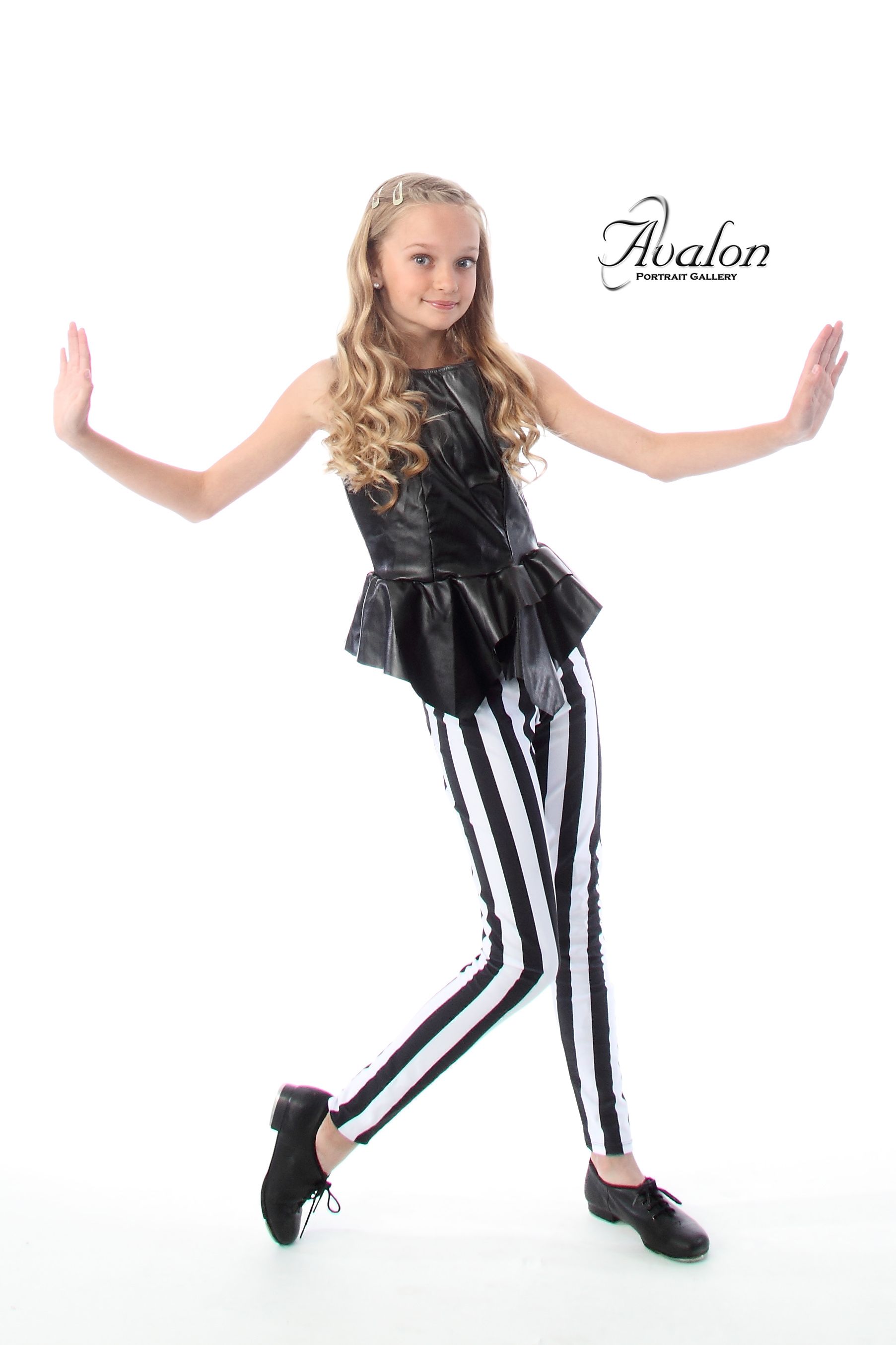 Dancer in striped pants and black top strikes stylish pose against white background.