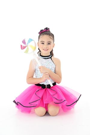 Young dancer in sparkly pink tutu dress holding colorful pinwheel prop.