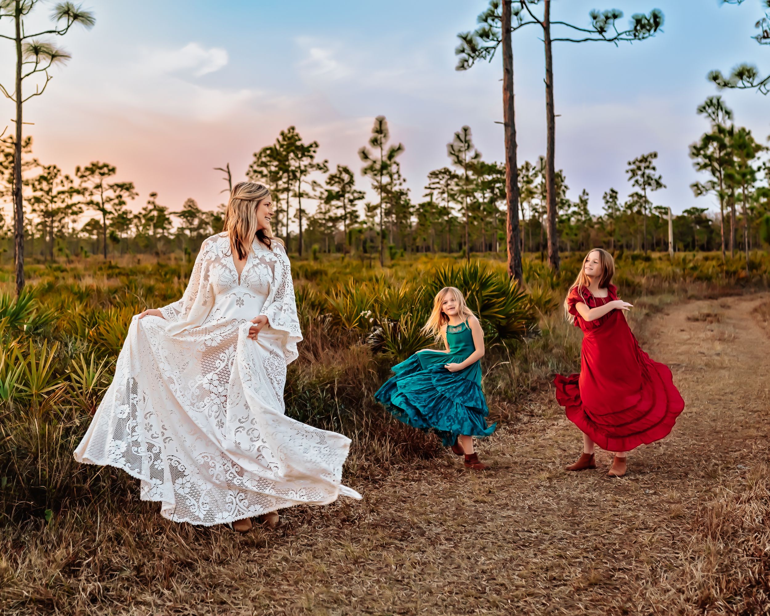 Mom and two daughters dancing in a field in Orlando, FL for an outdoor golden hour photography session.