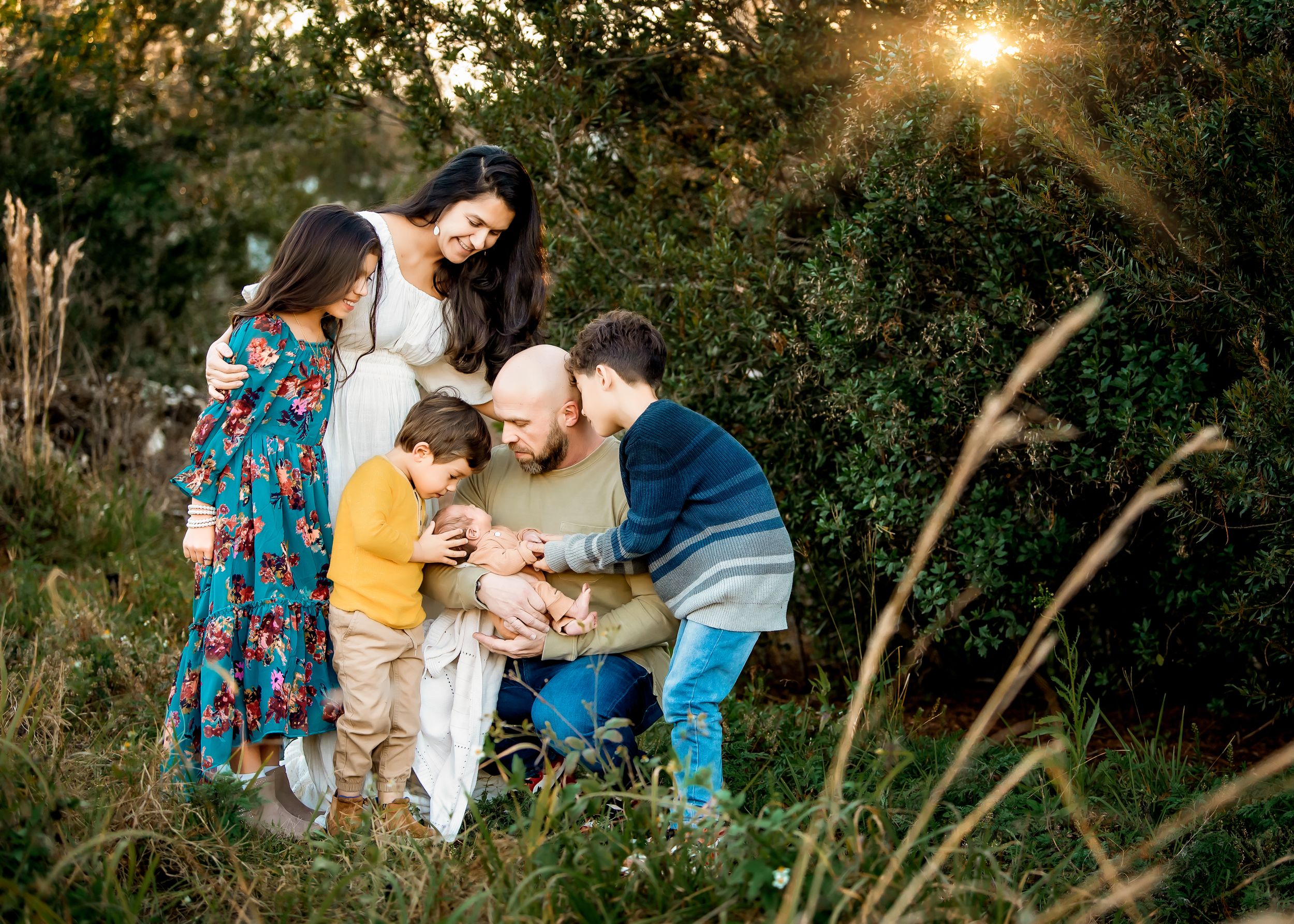 Family looking at newborn baby in a field during golden hour in Orlando, FL.