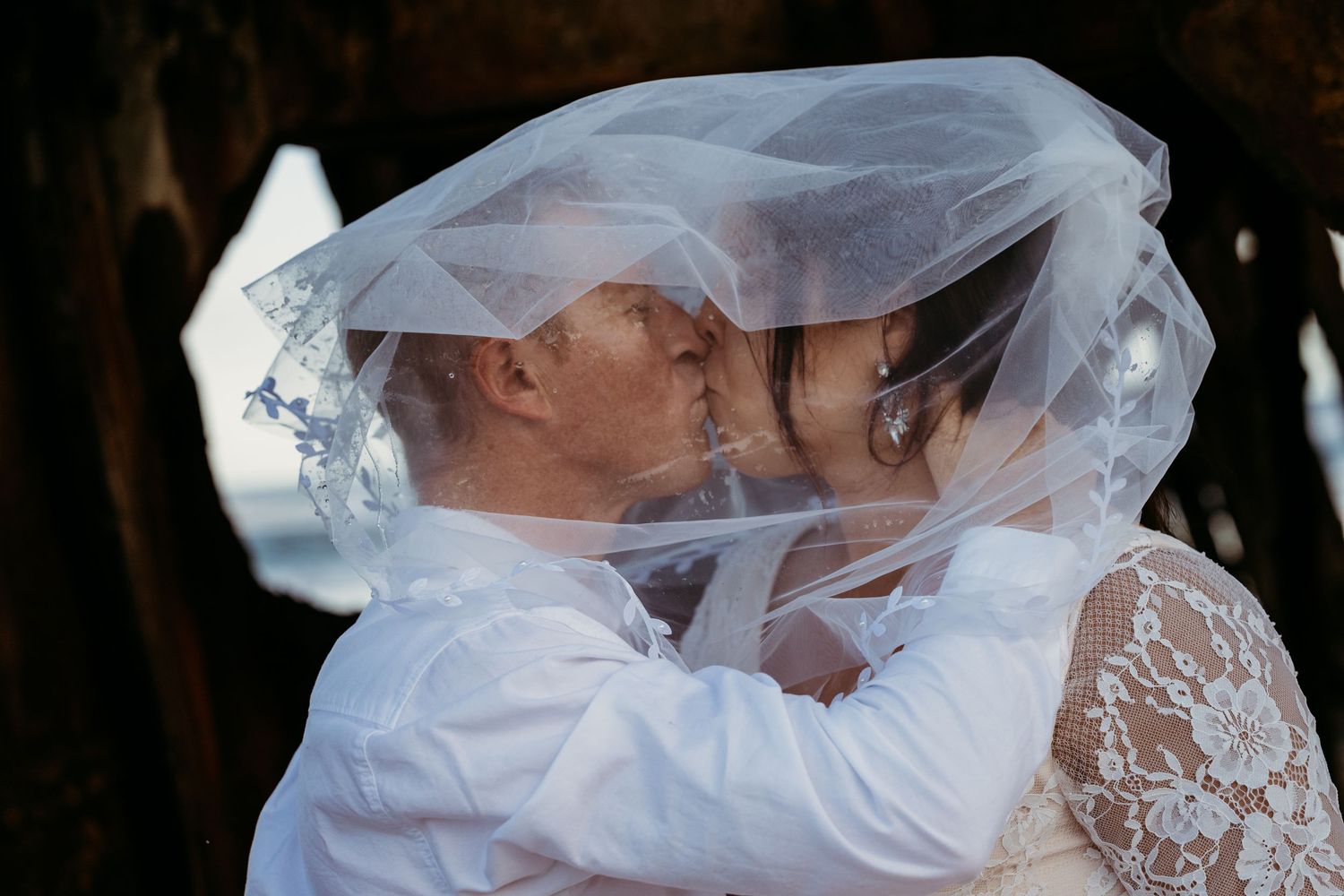 Intimate wedding moment shared under a delicate white veil.