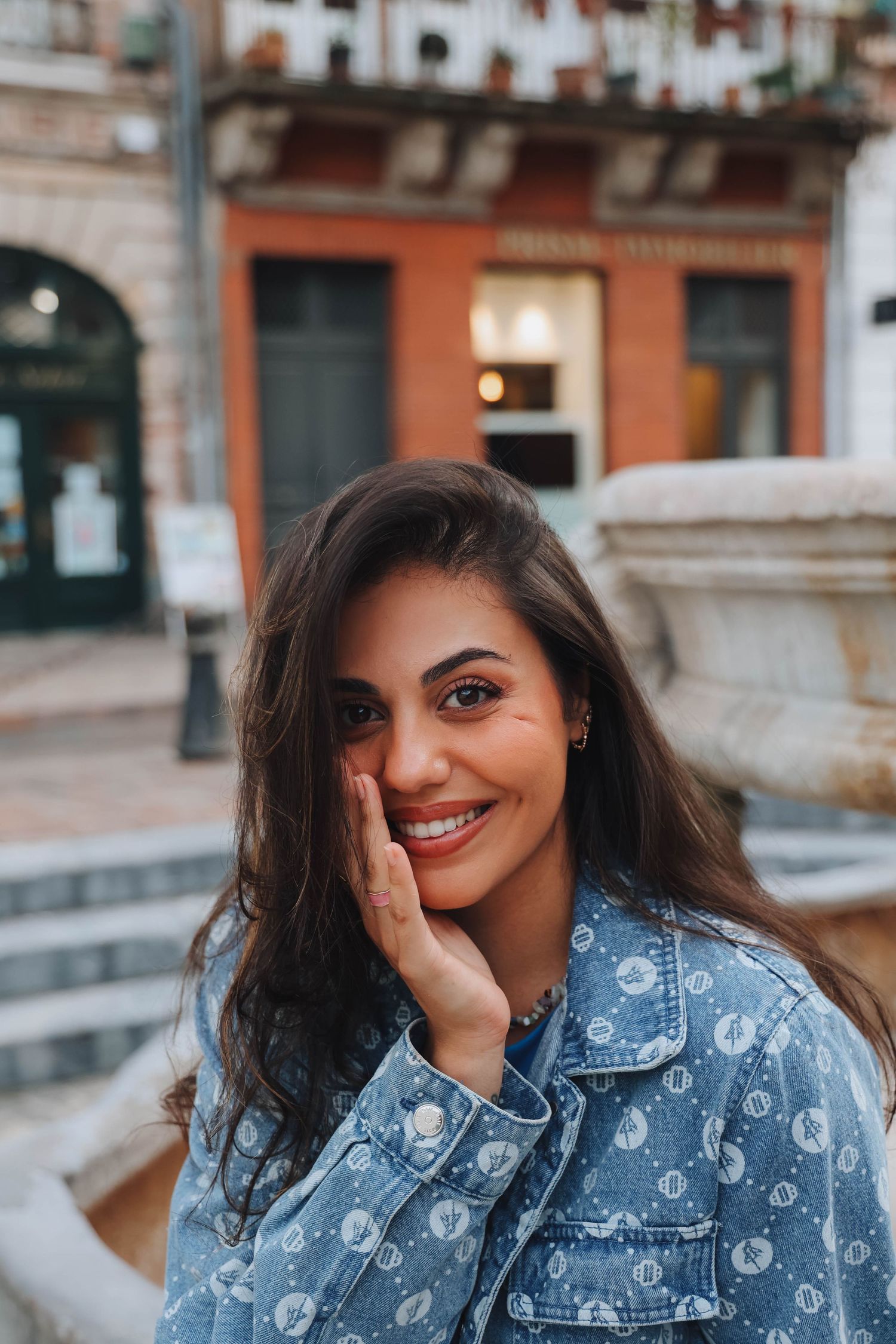Street portrait featuring denim jacket against urban architecture background.
