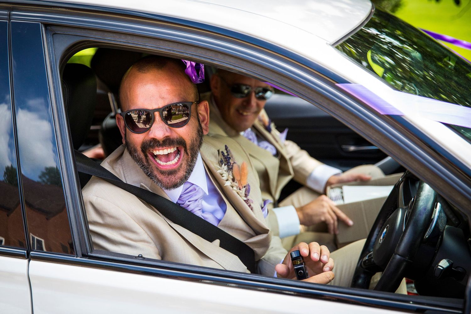 Happy newlyweds smile while seated in their wedding car.