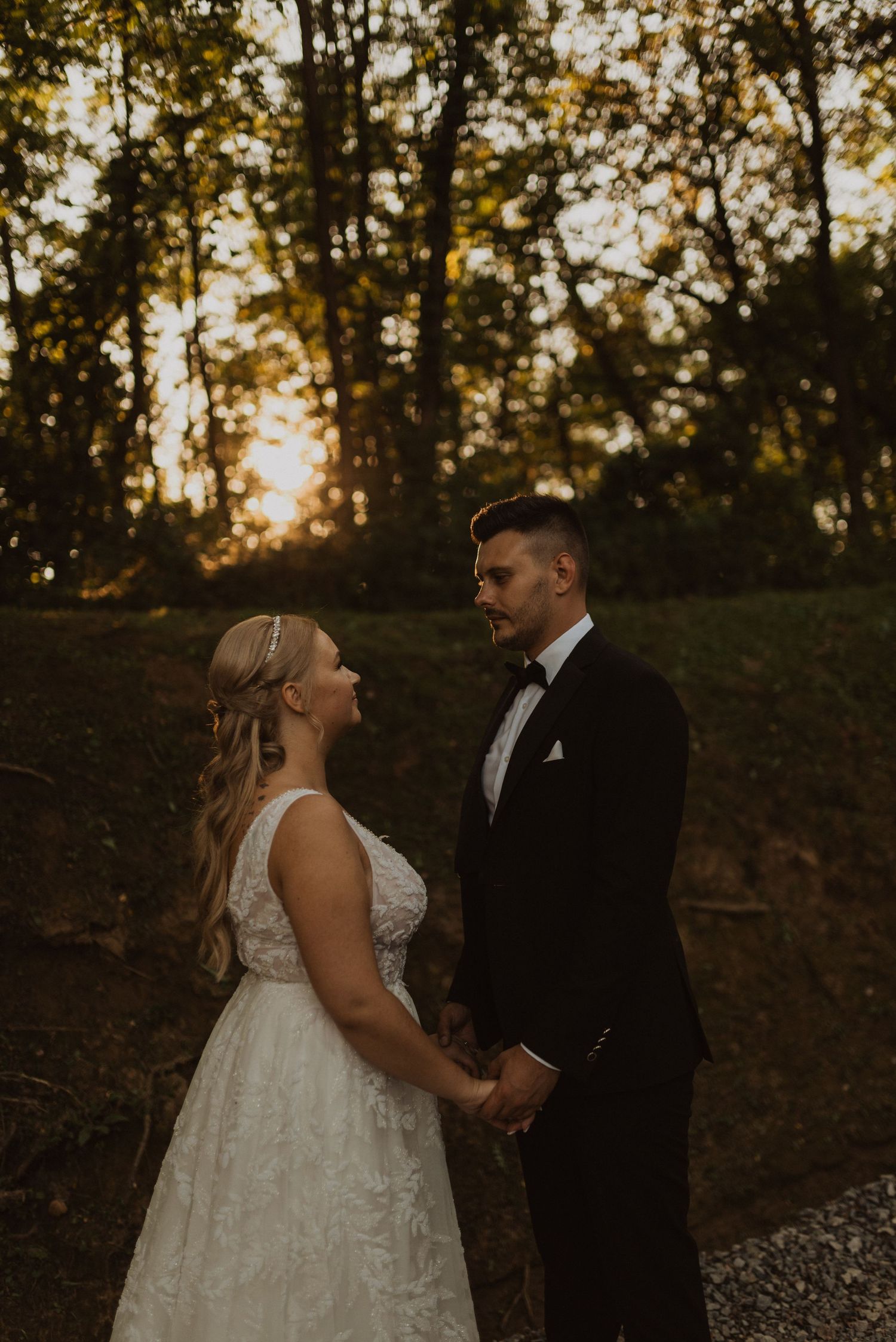 Sunset wedding portrait of couple holding hands in romantic forest setting.