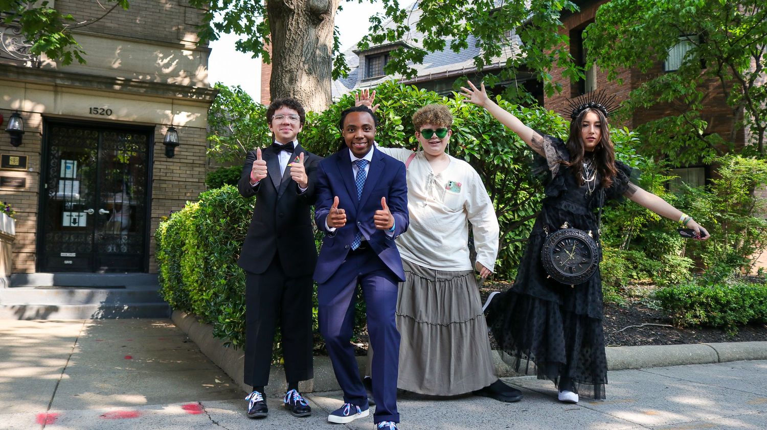 Group of people posing enthusiastically outside a building entrance.