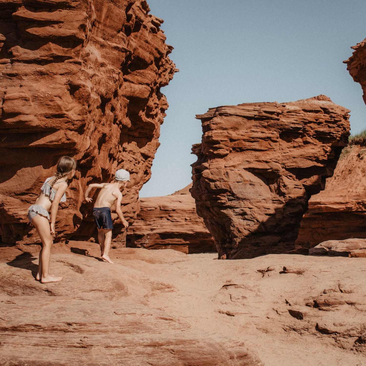 Hikers exploring red rock formations in a desert canyon landscape.