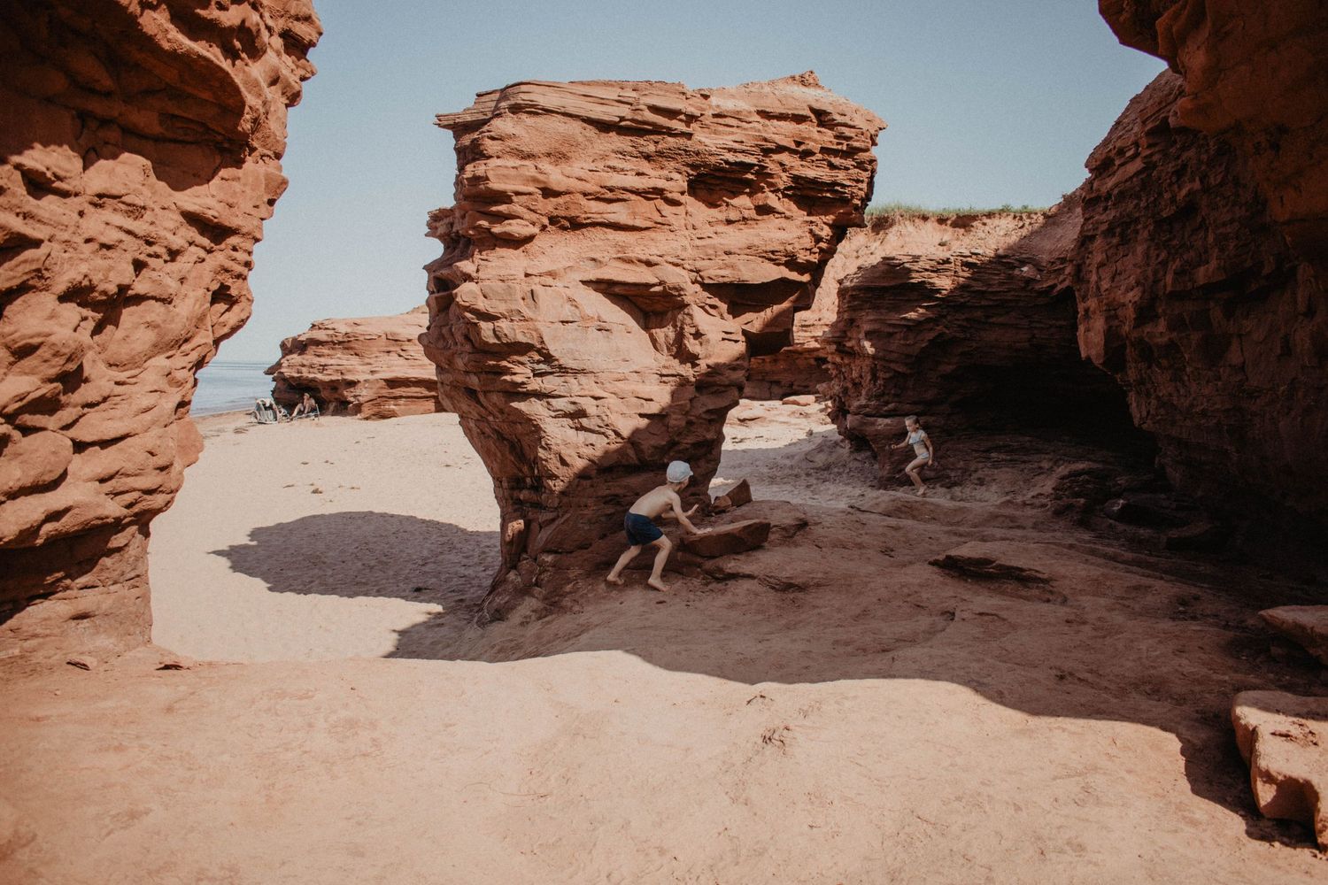 Natural stone arch formation in a desert landscape with red rocks and clear blue sky.