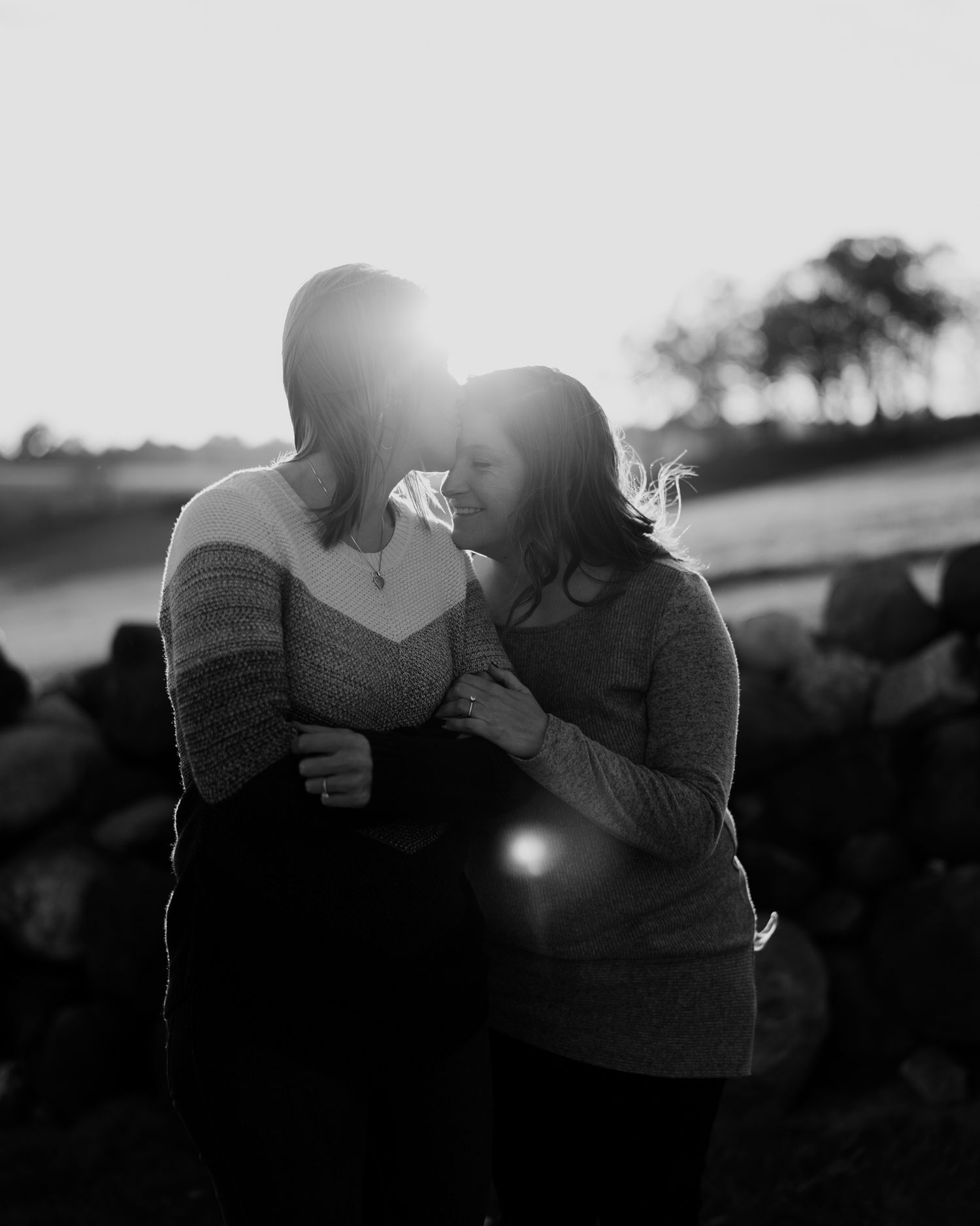 a warm embrace of a female couple in black and white in the autumn evening glow