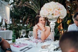 Wedding reception guest enjoying dinner at elegantly decorated table with floral centerpiece.