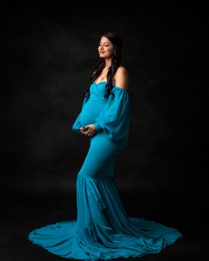 Elegant maternity photo with a turquoise form-fitting gown and dramatic train.