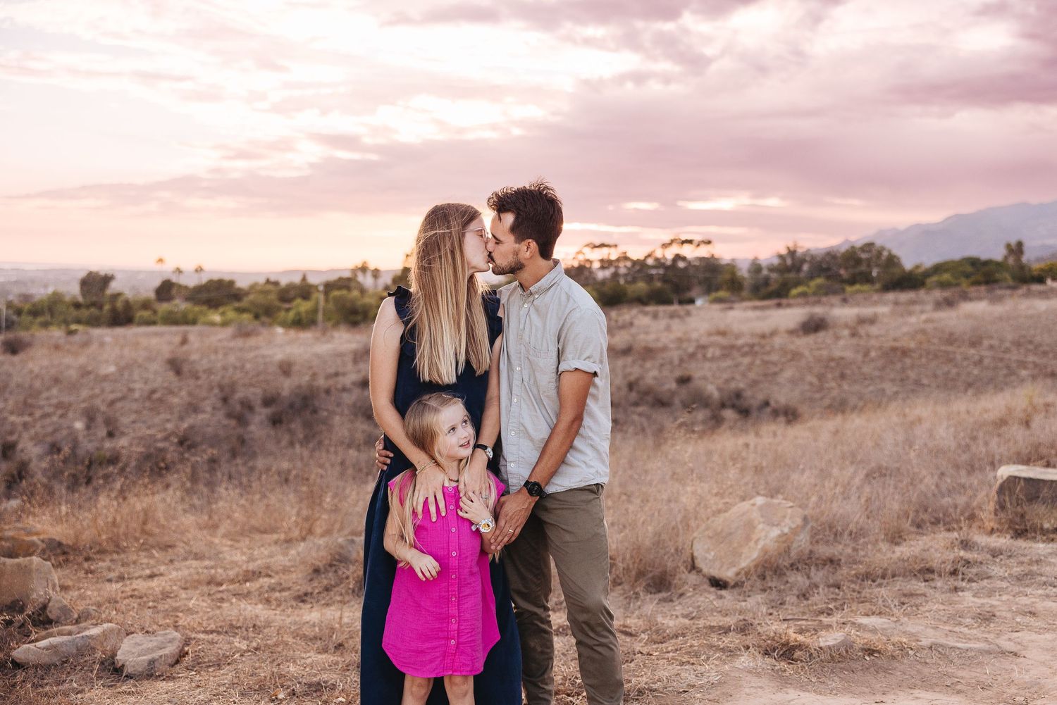 A family shares an intimate moment against a desert landscape at sunset.