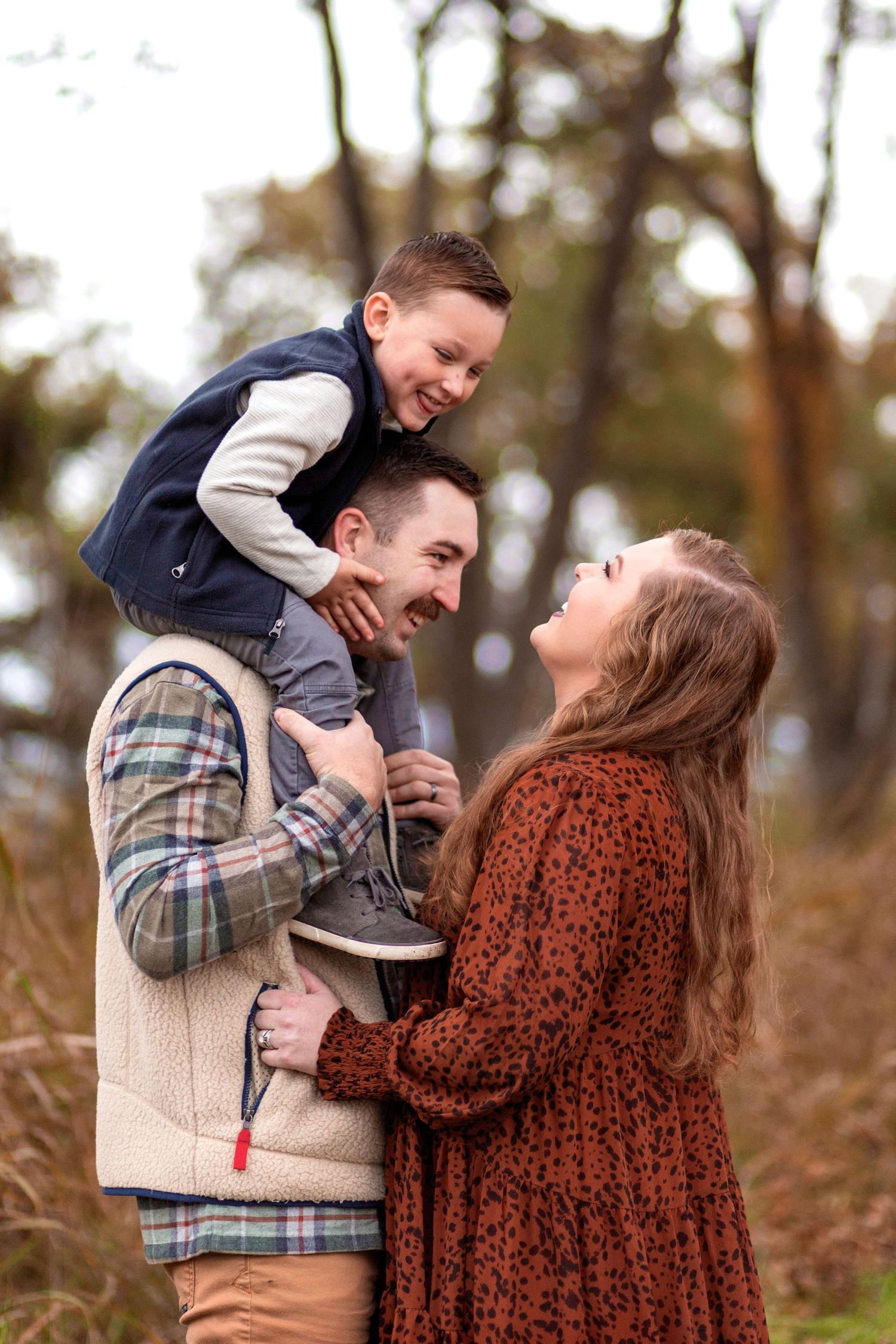 Happy family enjoying playful moment outdoors in autumn setting.