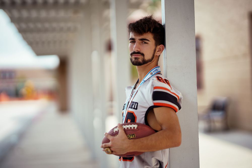 A candid portrait shows an athletic person leaning against a white column in casual sportswear.