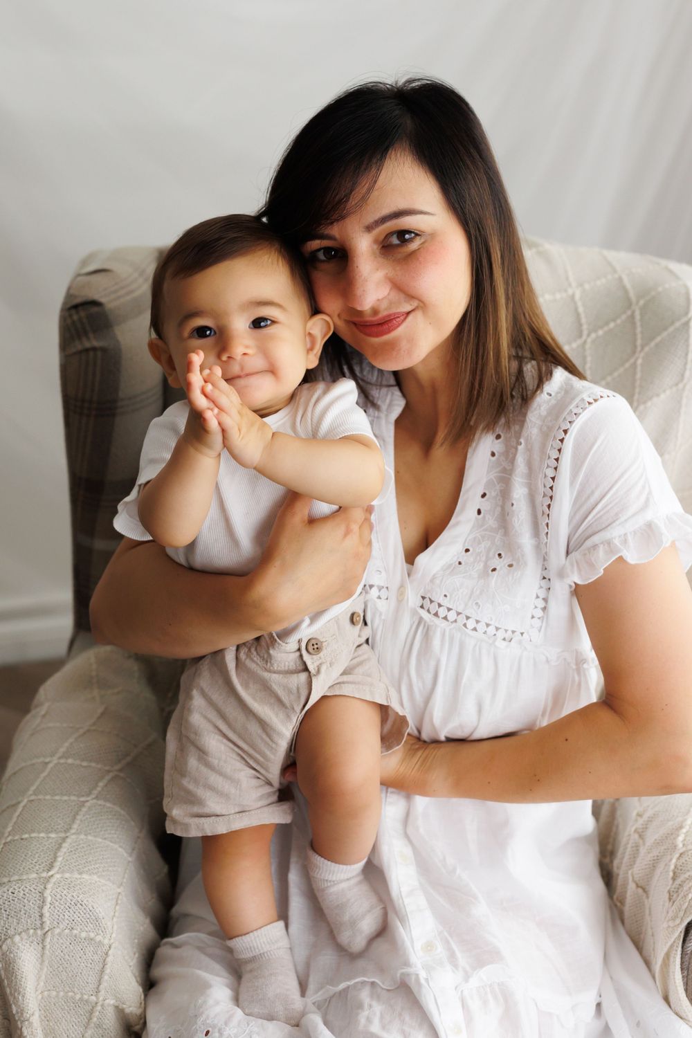 Tender moment captured in armchair during bright indoor family photo session.