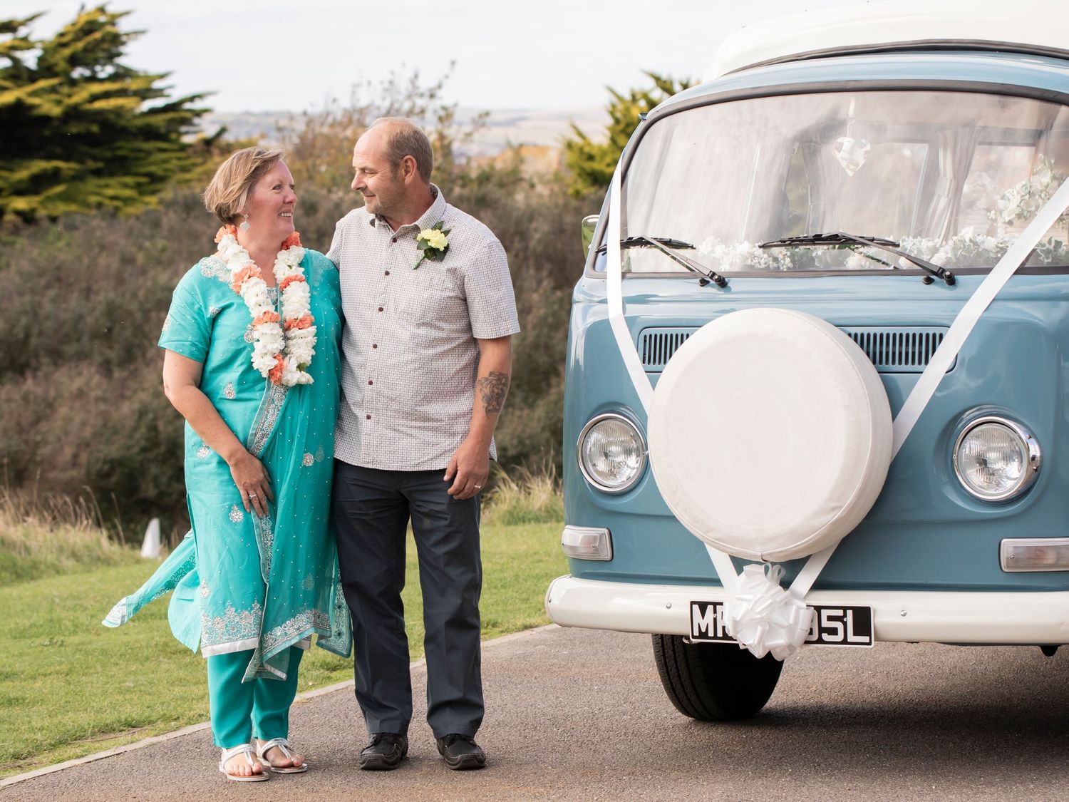 bride and groom with blue campervan