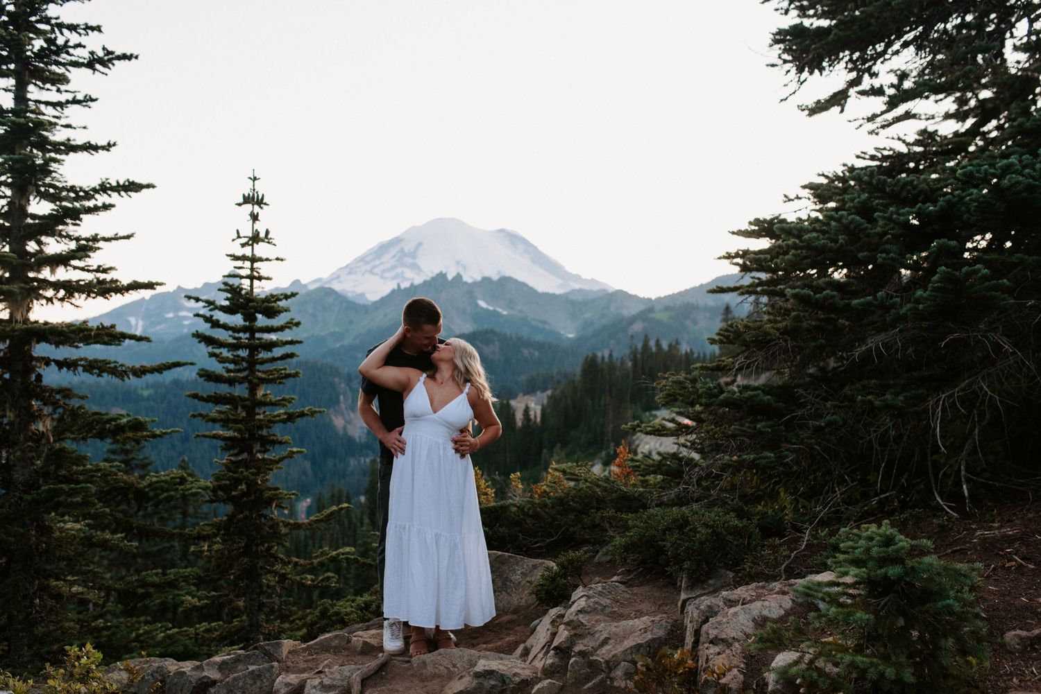 Scenic mountain landscape with evergreen trees and rocky terrain at sunset.