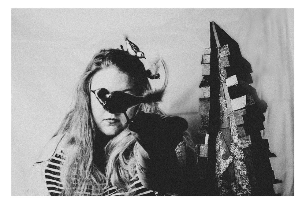 Artistic black and white portrait featuring sunglasses and striped shirt against textured background.