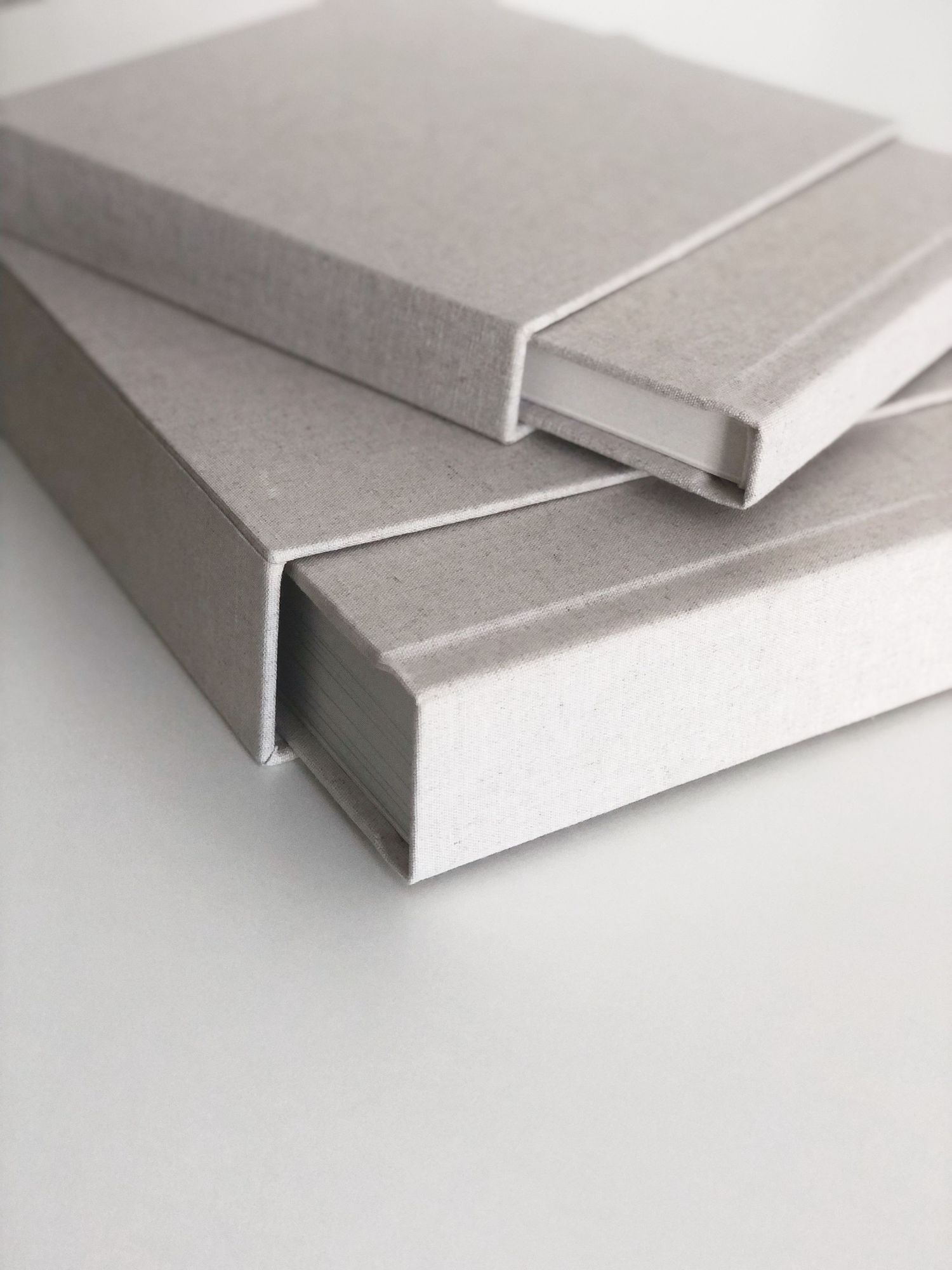 Contemporary gray cloth-bound books with elegant spine design on white surface.