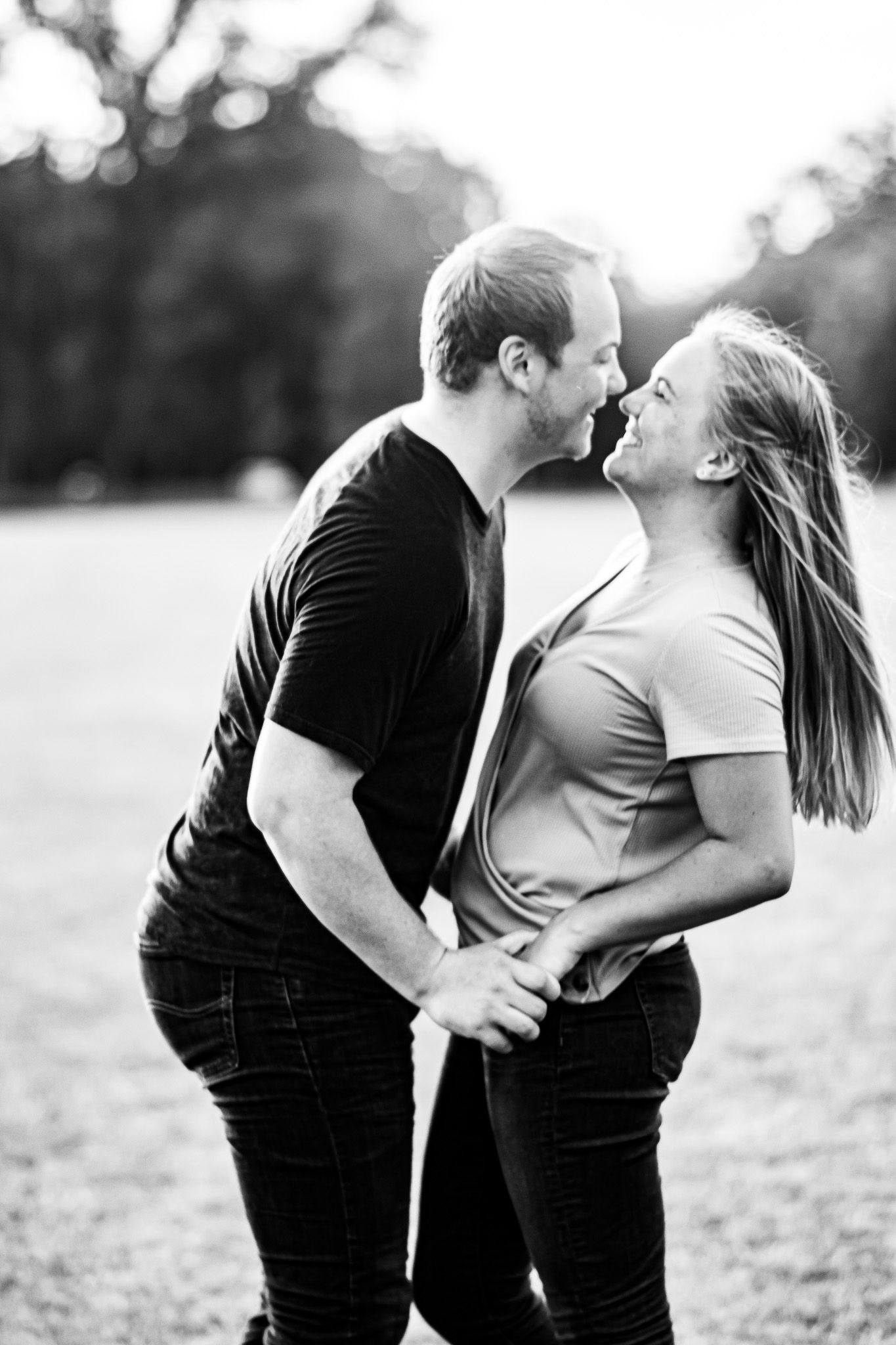 Romantic couple shares intimate moment in black and white portrait outdoors.