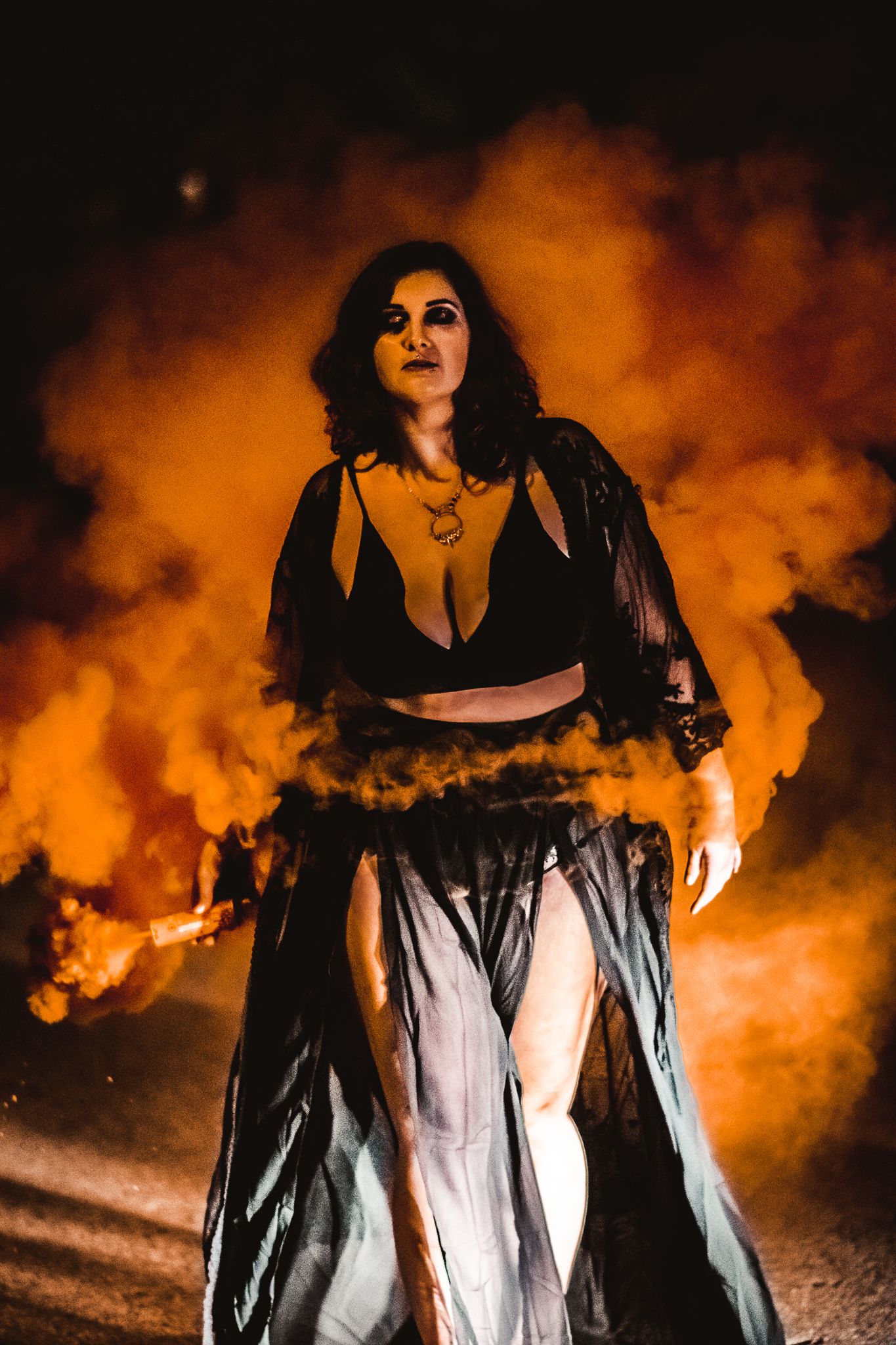 A dramatic portrait with orange smoke effects showing a woman in gothic-inspired clothing.