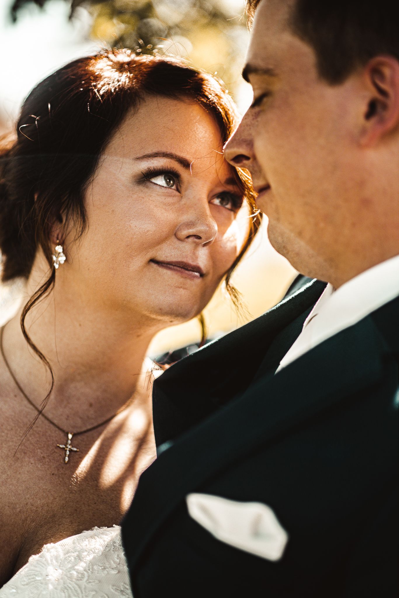 An intimate wedding portrait capturing a romantic moment between newlyweds in golden sunlight.