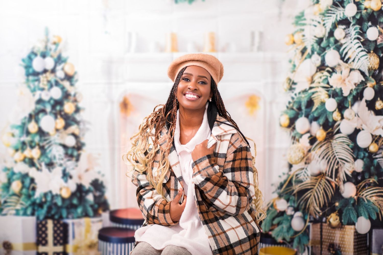 Festive holiday photoshoot with plaid outfit and decorated Christmas trees in background.
