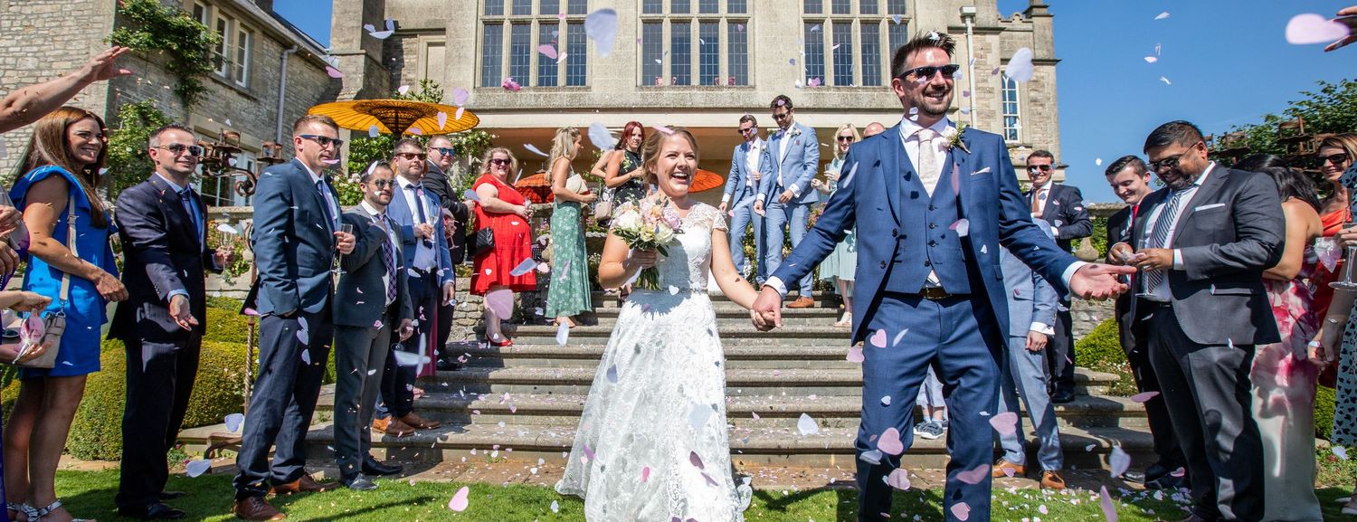 Newlyweds celebrate while guests throw confetti on church steps.