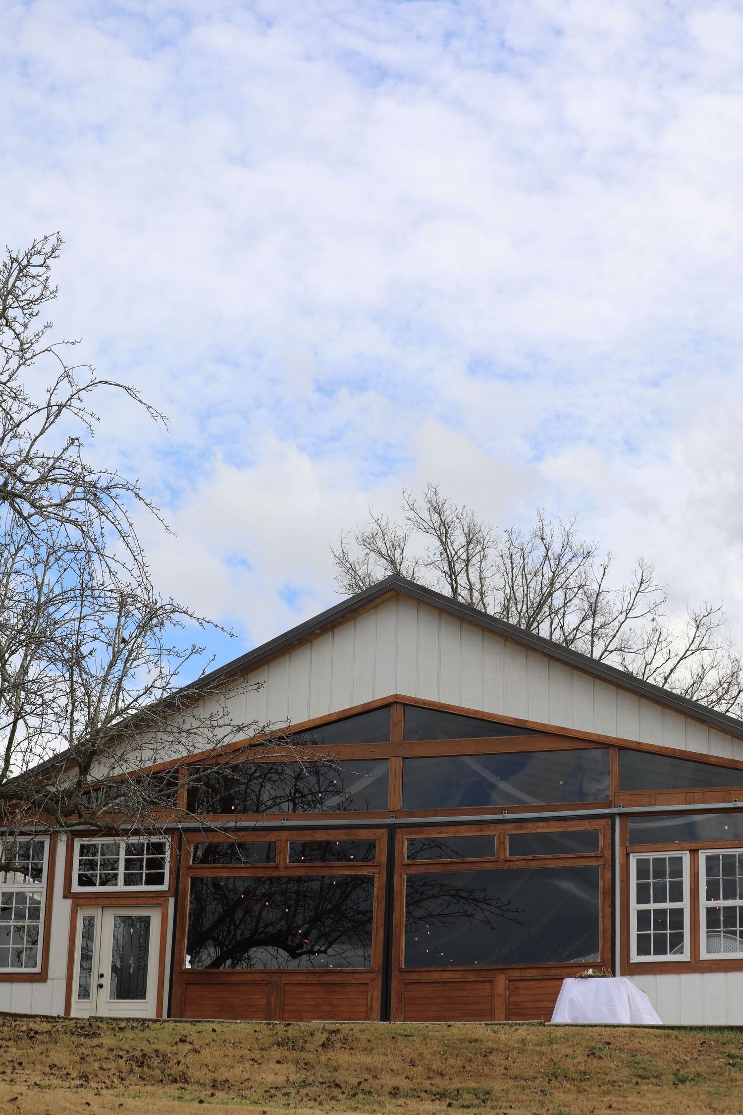 Long white ranch-style building with wooden beams and windows against a blue sky.