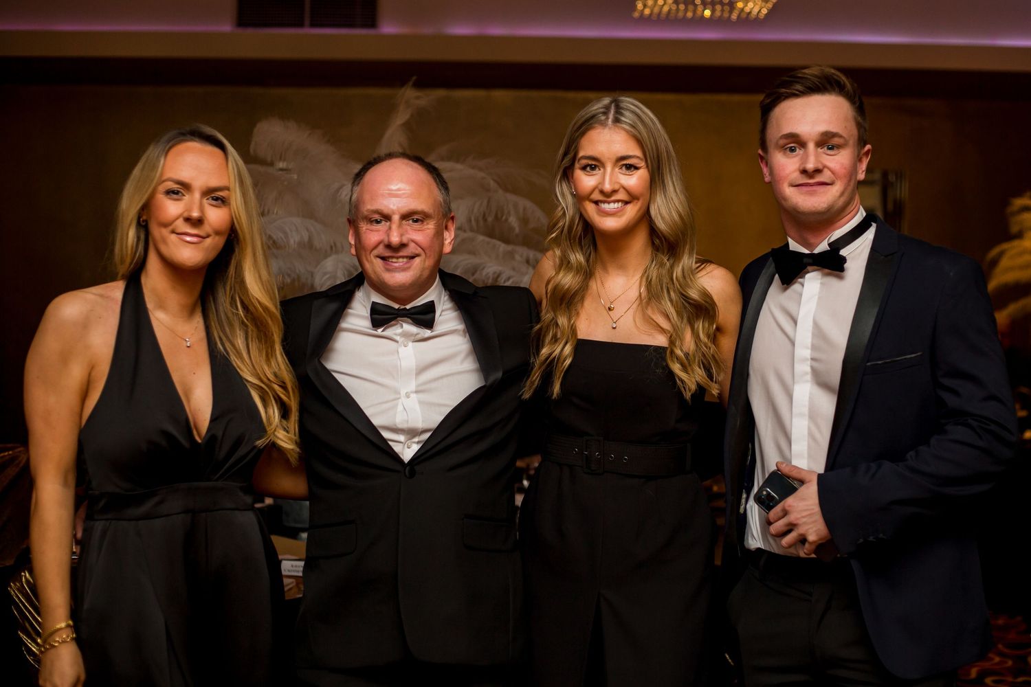 Formal evening event with people in black tie attire posing together.