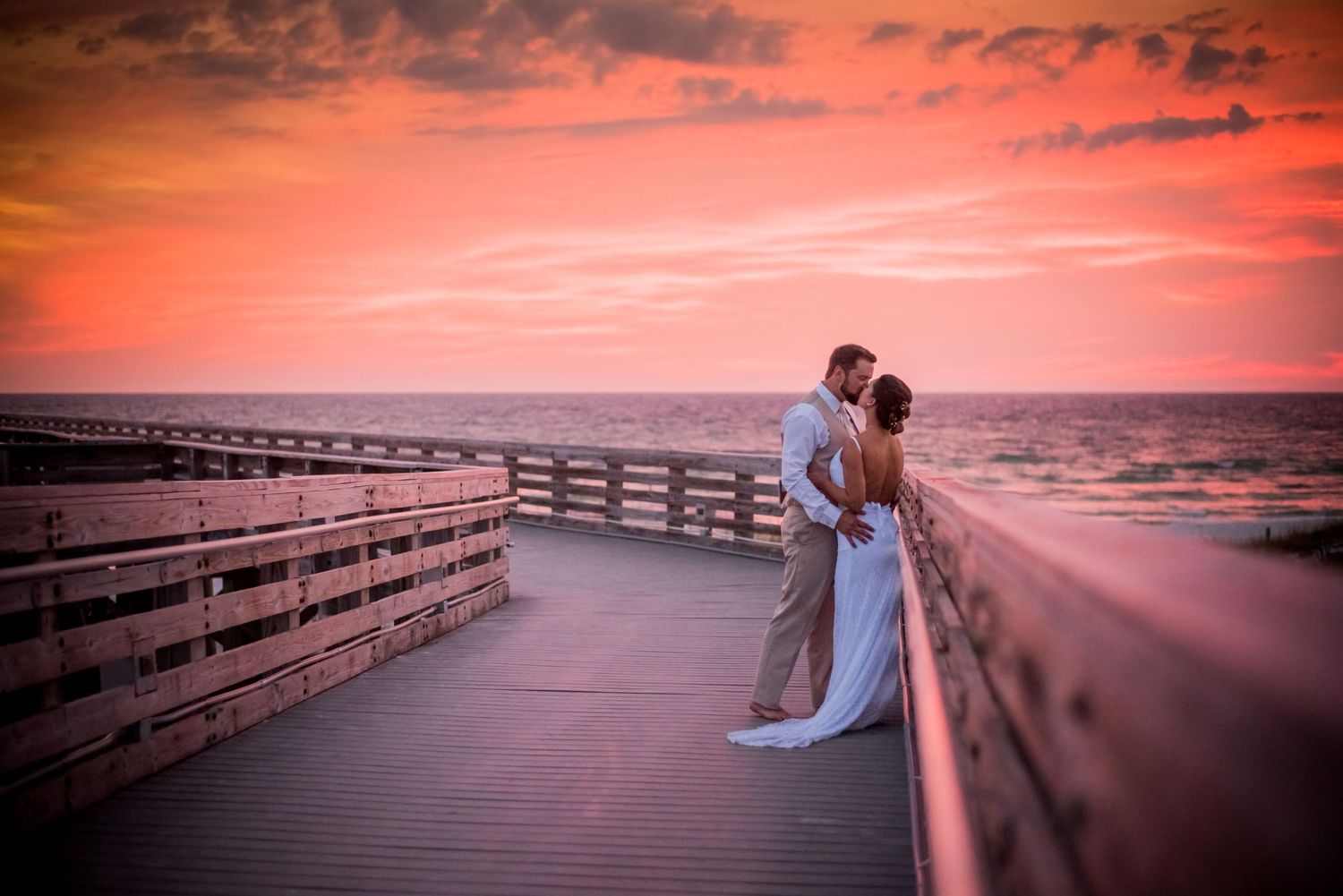 beautiful couple kissing on pier on their wedding day at sunset on Panama City Beach Florida