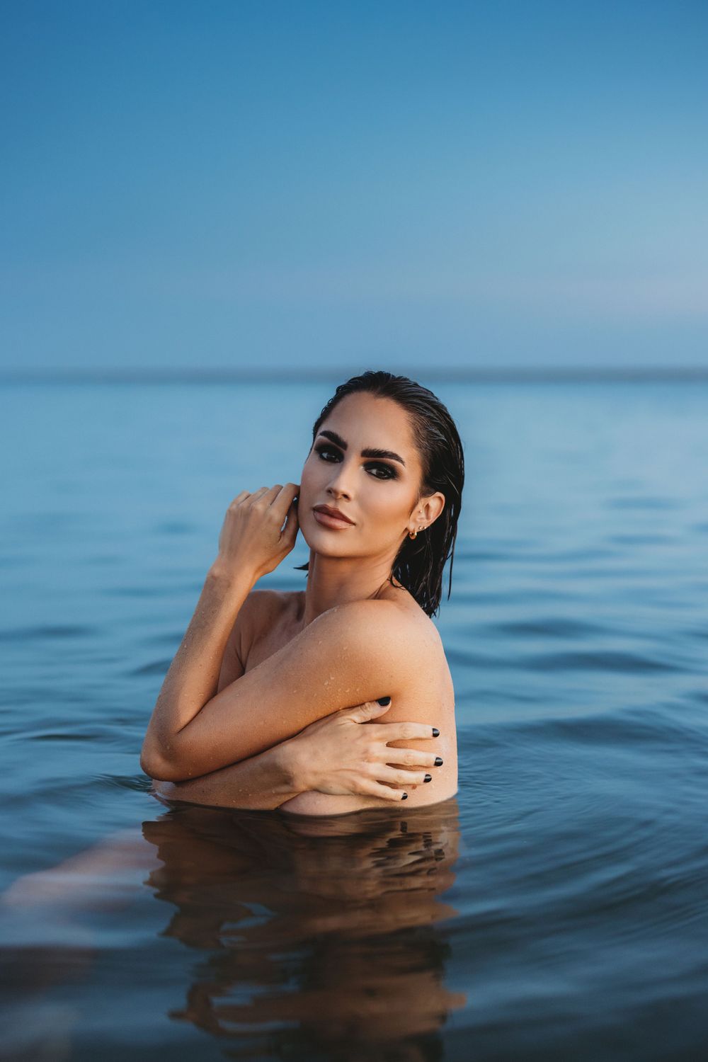 Artistic portrait of woman in water against blue ocean backdrop.
