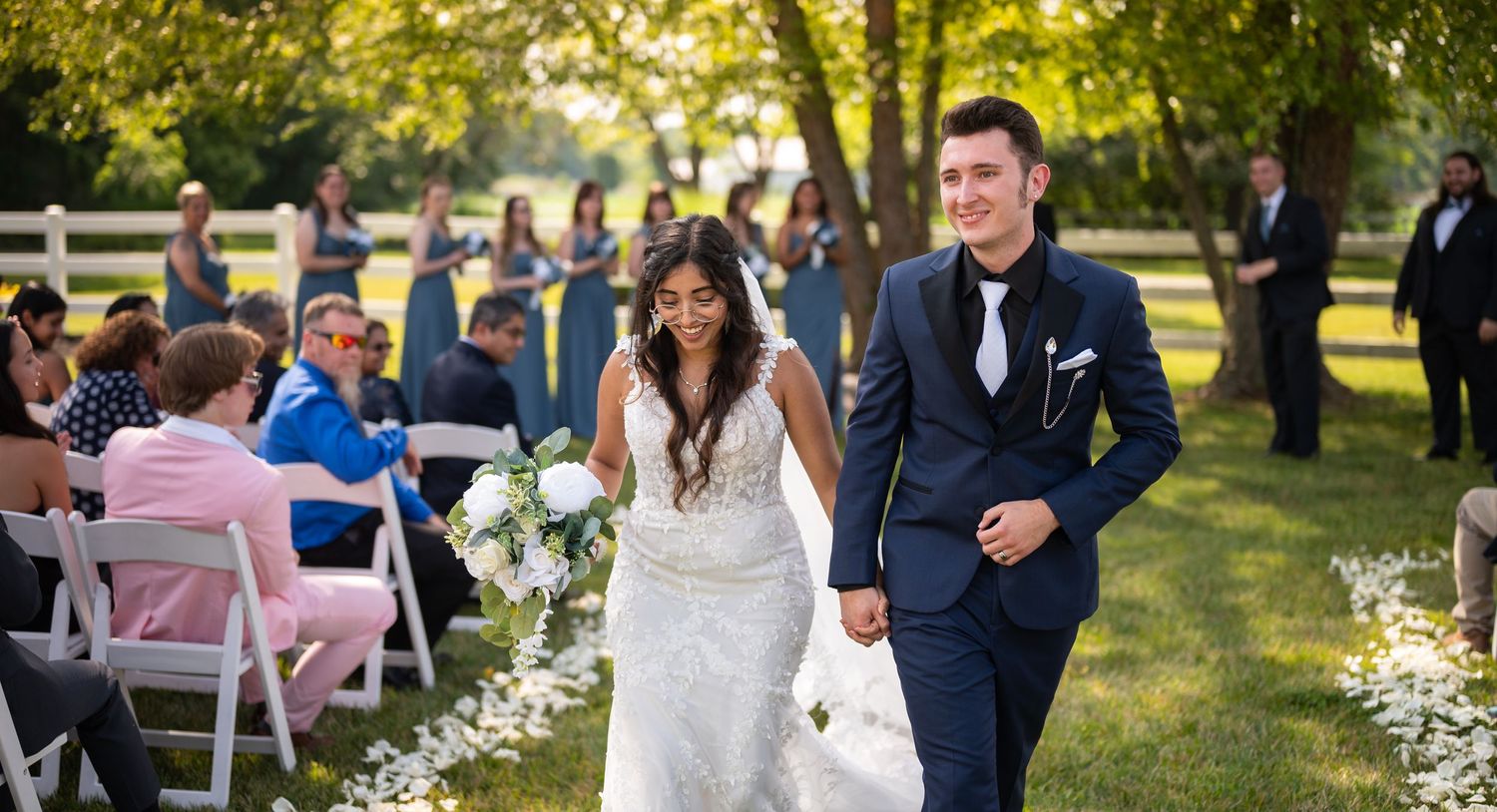 Elegant outdoor wedding ceremony setup with white chairs and floral decorations in a garden setting.