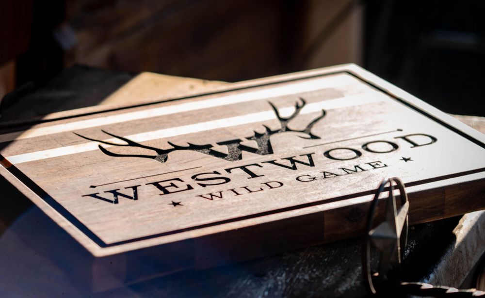 A wooden cutting board with Westwood Wild Game logo and antler design engraved.