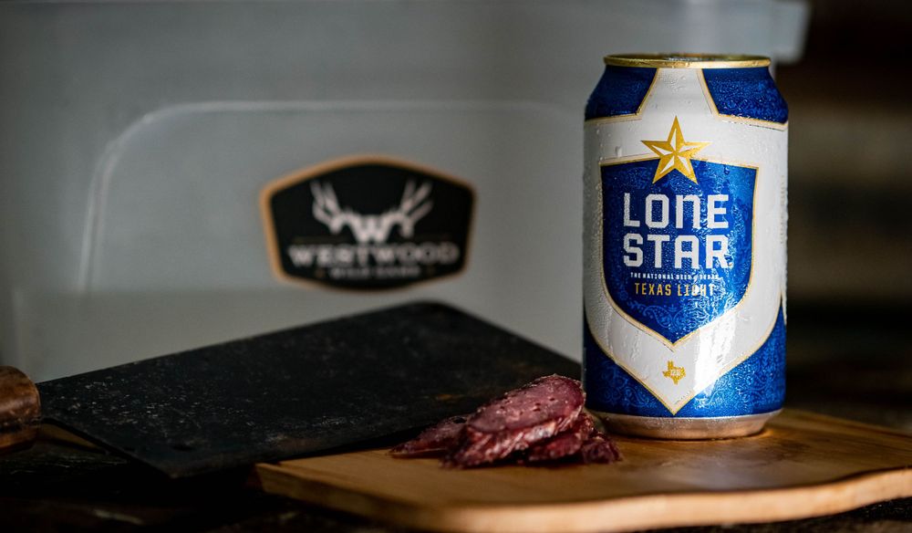 Lone Star beer can with sliced cured meat on cutting board.