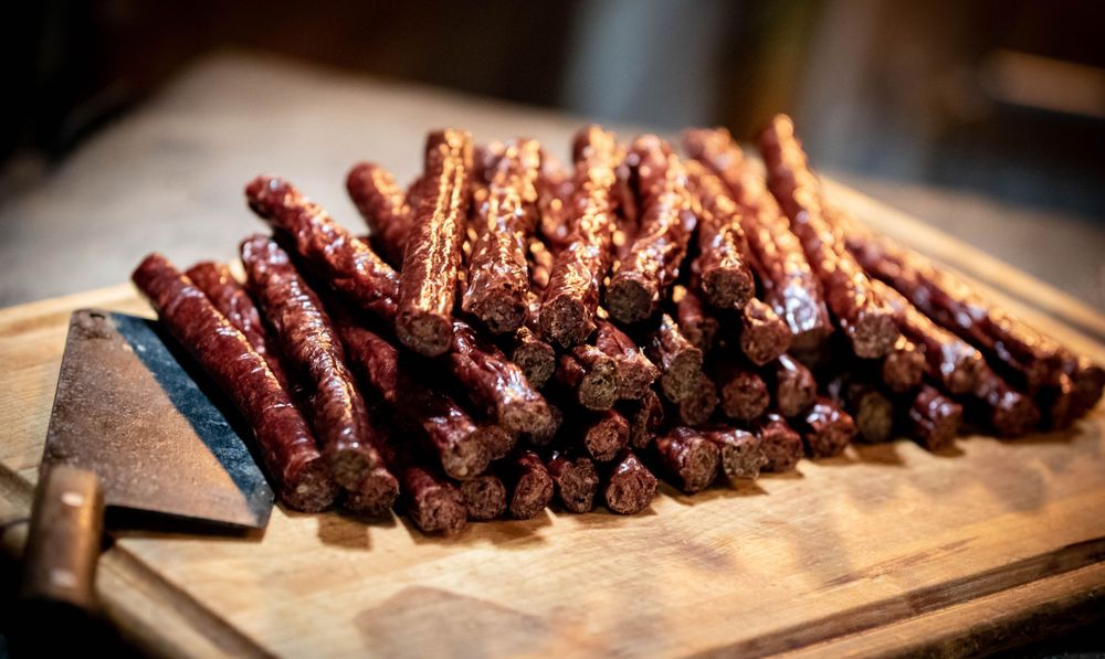 Stack of smoked sausage links on wooden cutting board.