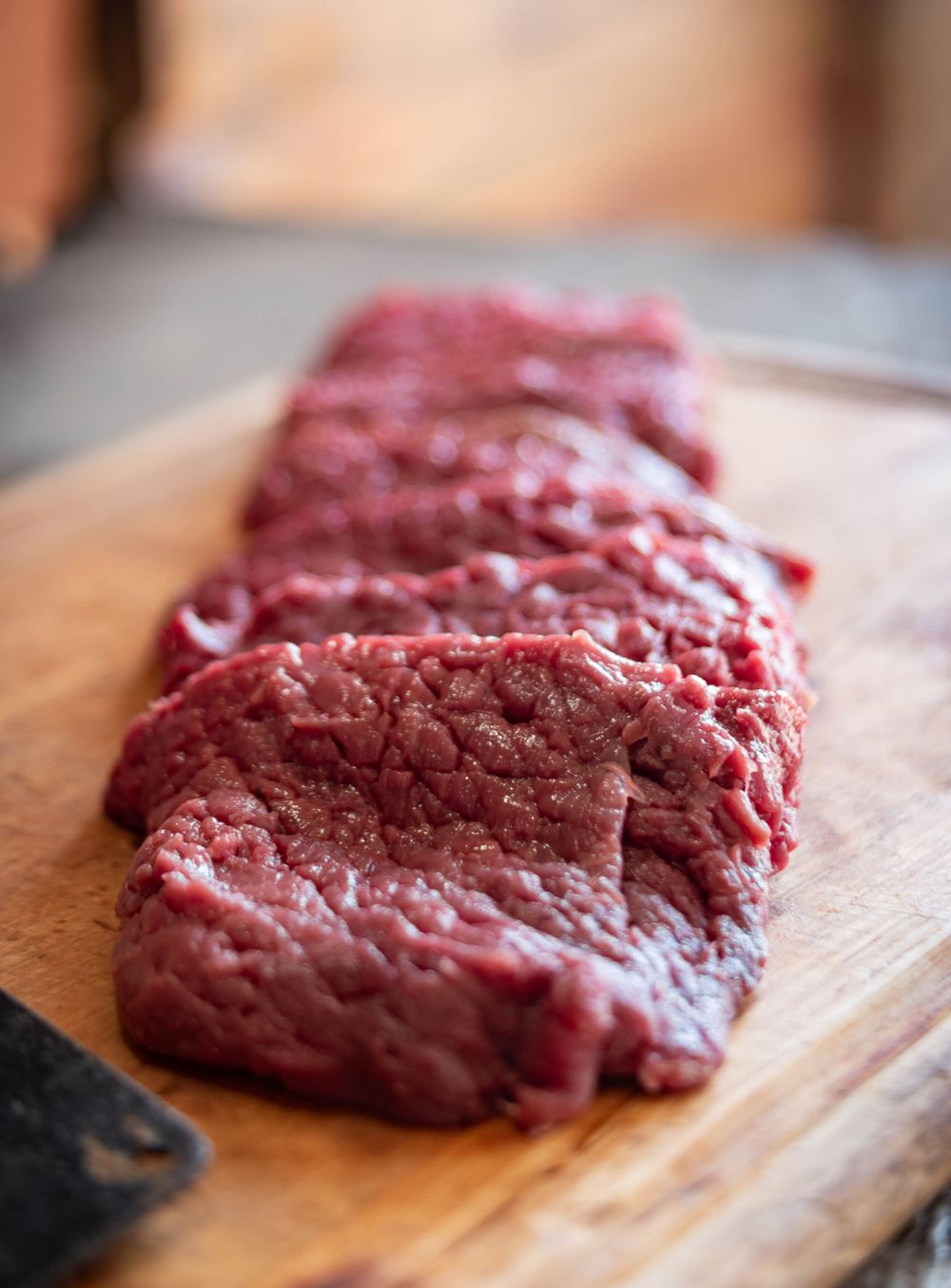Fresh raw venison steaks laid out on a wooden cutting board.