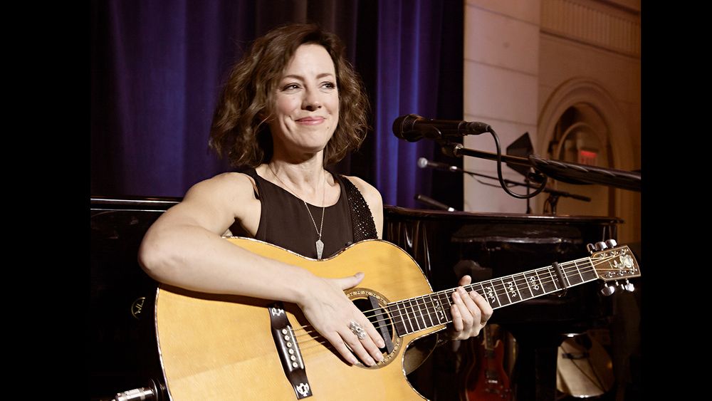 Musician performs on acoustic guitar during concert in intimate venue setting.