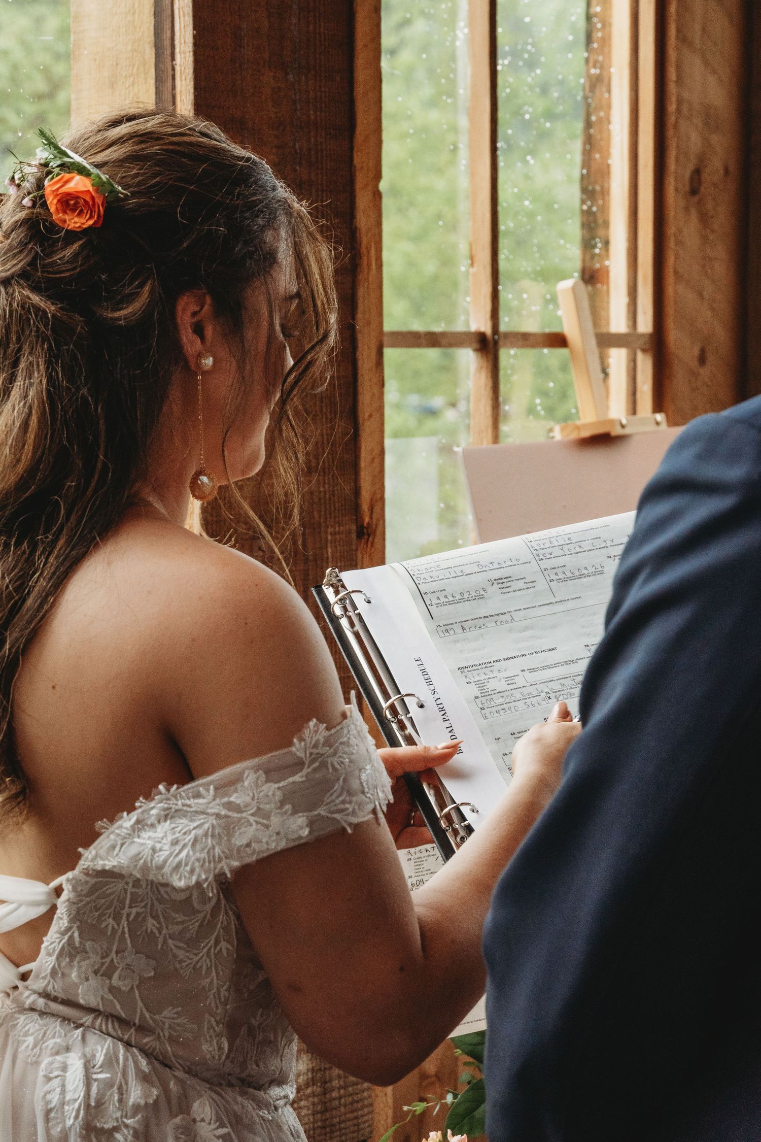 Close up of signing marriage certificate during wedding ceremony with lace dress detail.