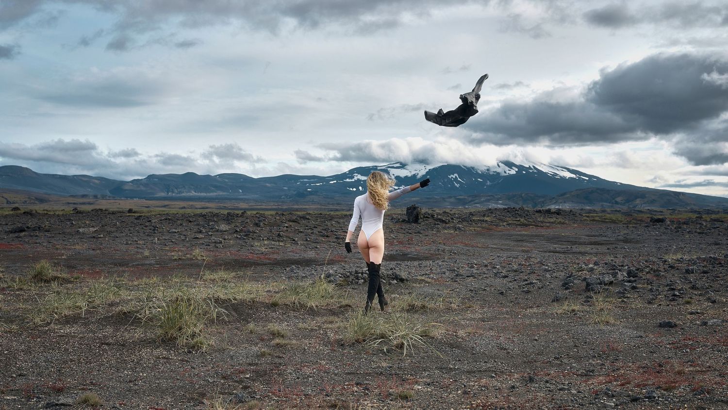 Creative levitation photography in volcanic landscape with snow-capped mountains.