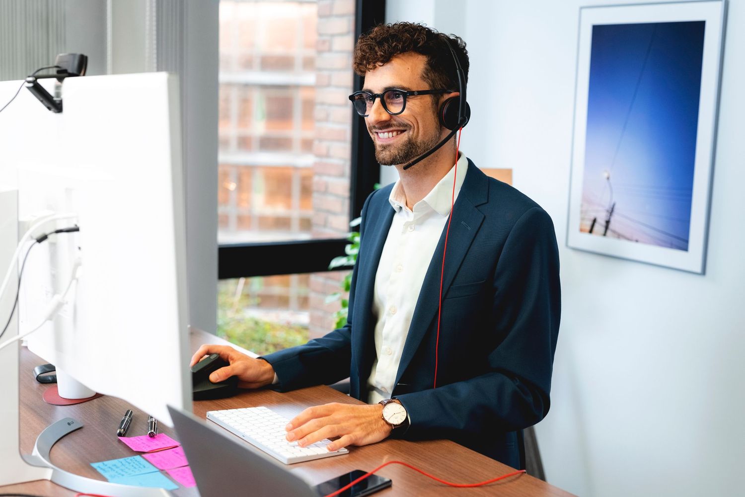 Professional wearing headset works at computer desk in modern office setting.