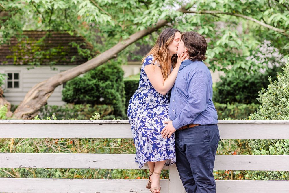 A couple shares an intimate moment while sitting on a wooden fence.