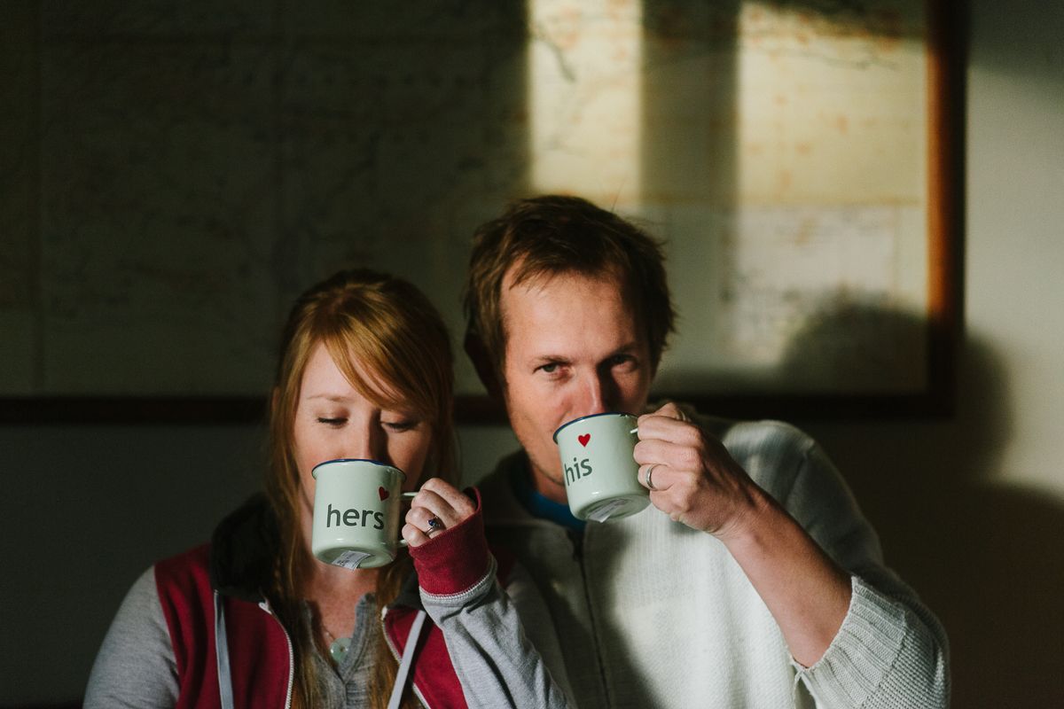 Two people drinking from coffee mugs in moody indoor lighting.