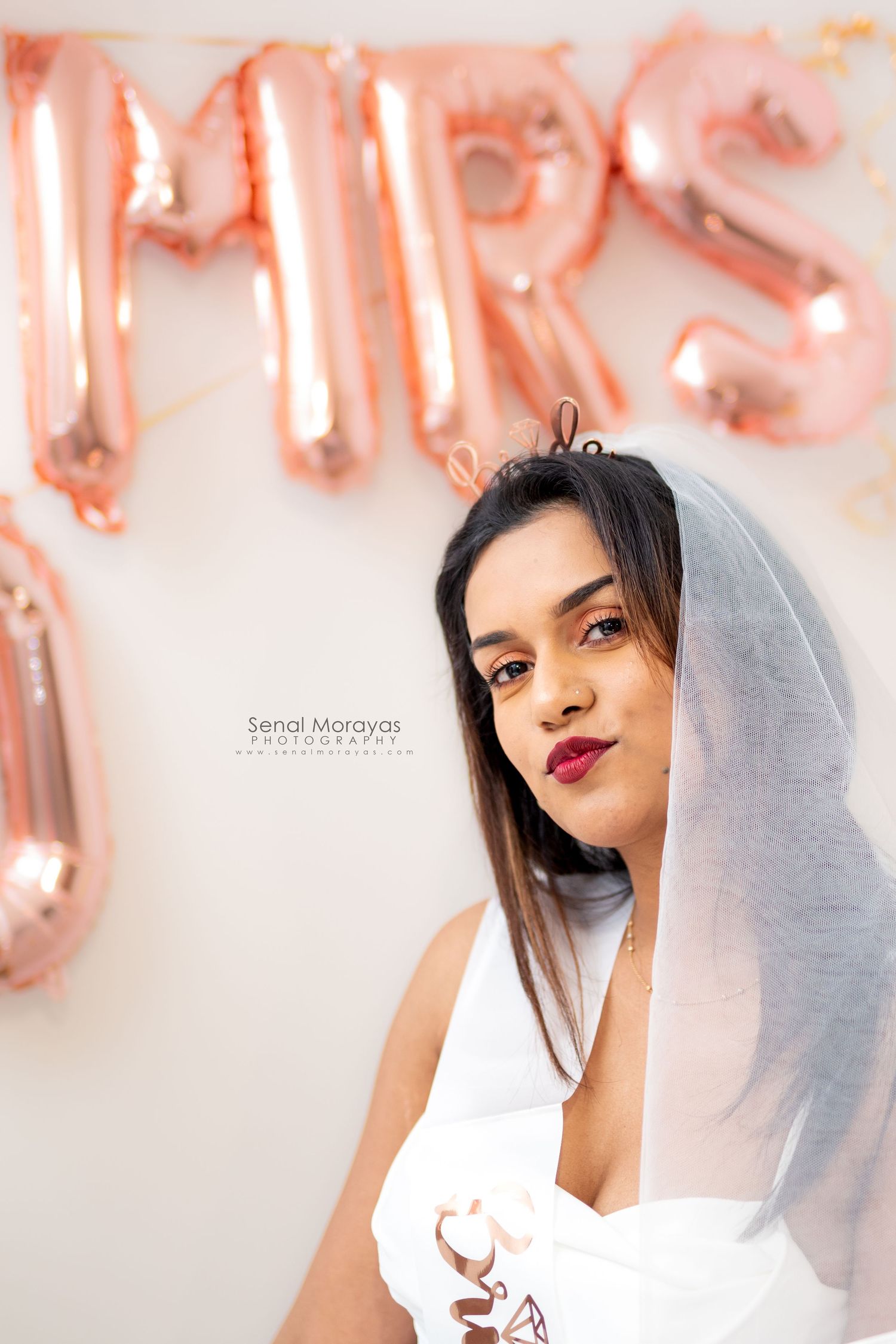 Studio portrait session with rose gold balloon decorations and soft lighting.