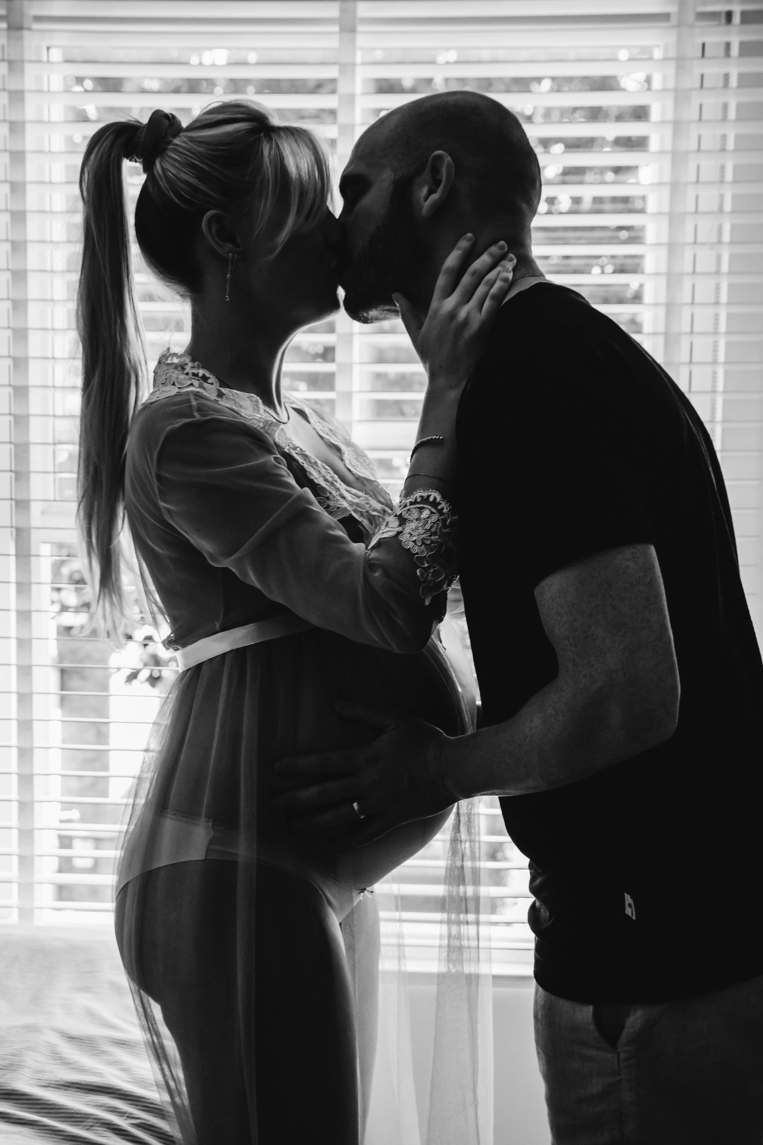 Black and white intimate moment between couple by window during pregnancy, in Stoke Newington, London.