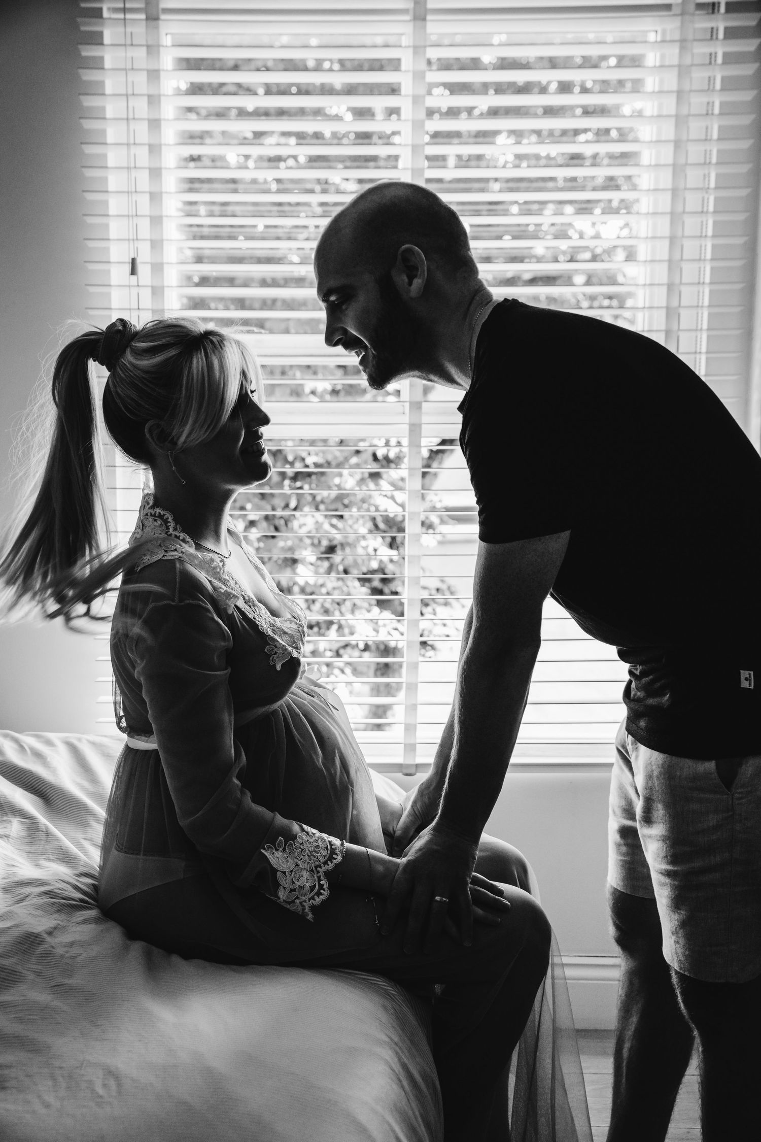 Tender black and white maternity scene with couple by sunlit window, in Stoke Newington, London.